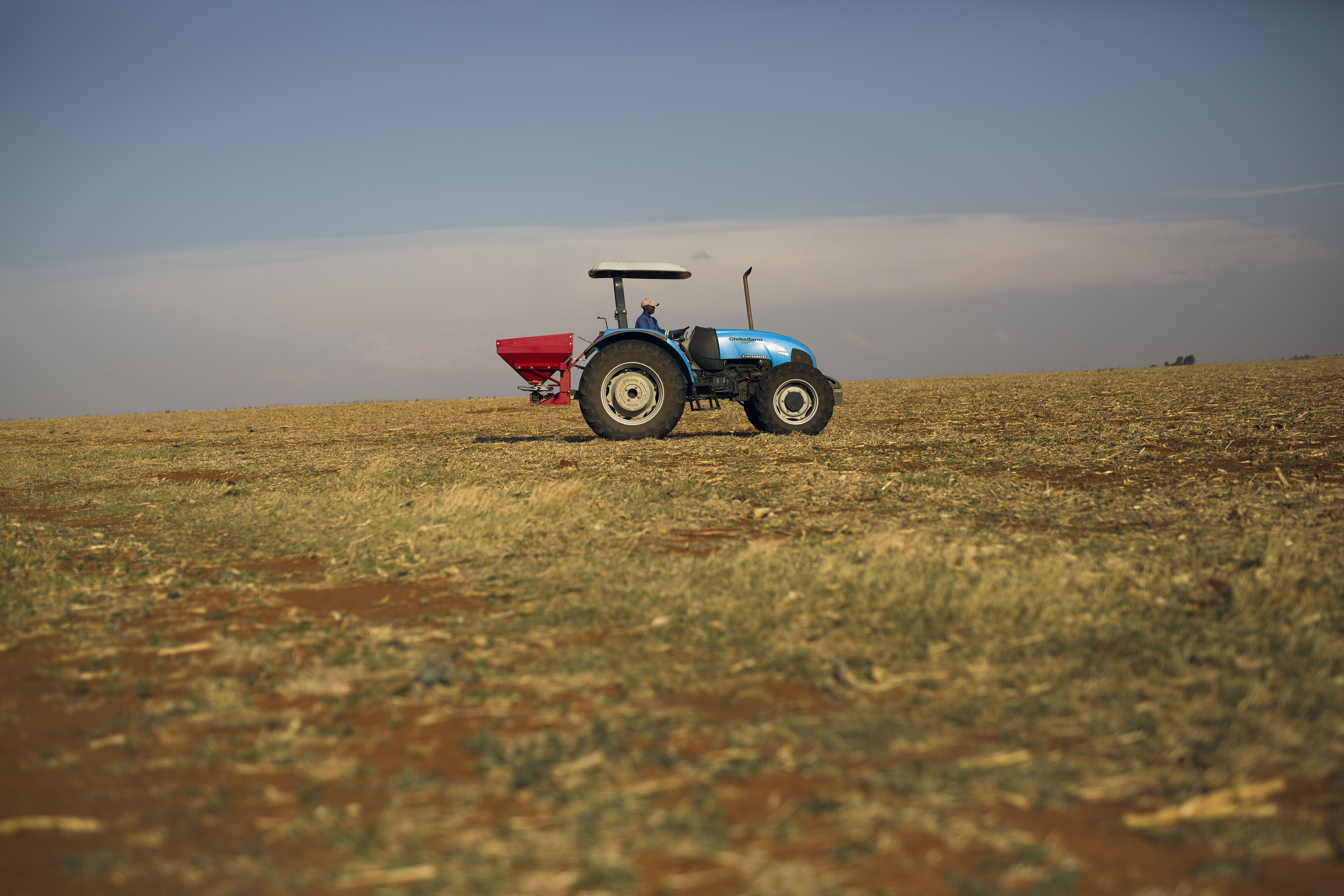A farm employee spreads fertiliser on the farm of John Rankin, a commercial farmer producing maize and corn on an industrial level, in Gerdau, North West province, South Africa, on November 19, 2018