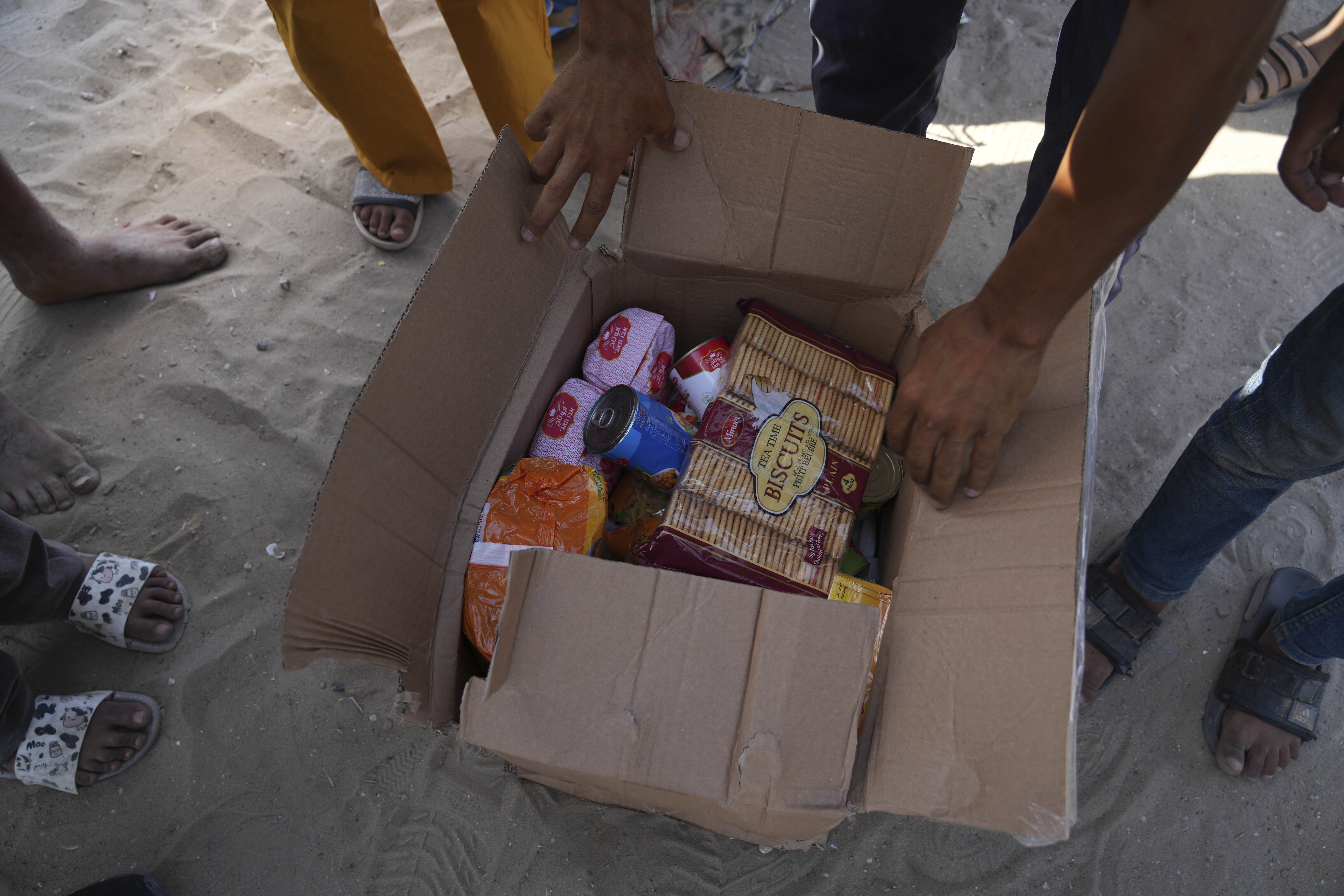Palestinians open a box containing food and humanitarian aid packages delivered by the Gaza Humanitarian Foundation in Rafah on May 27, 2025