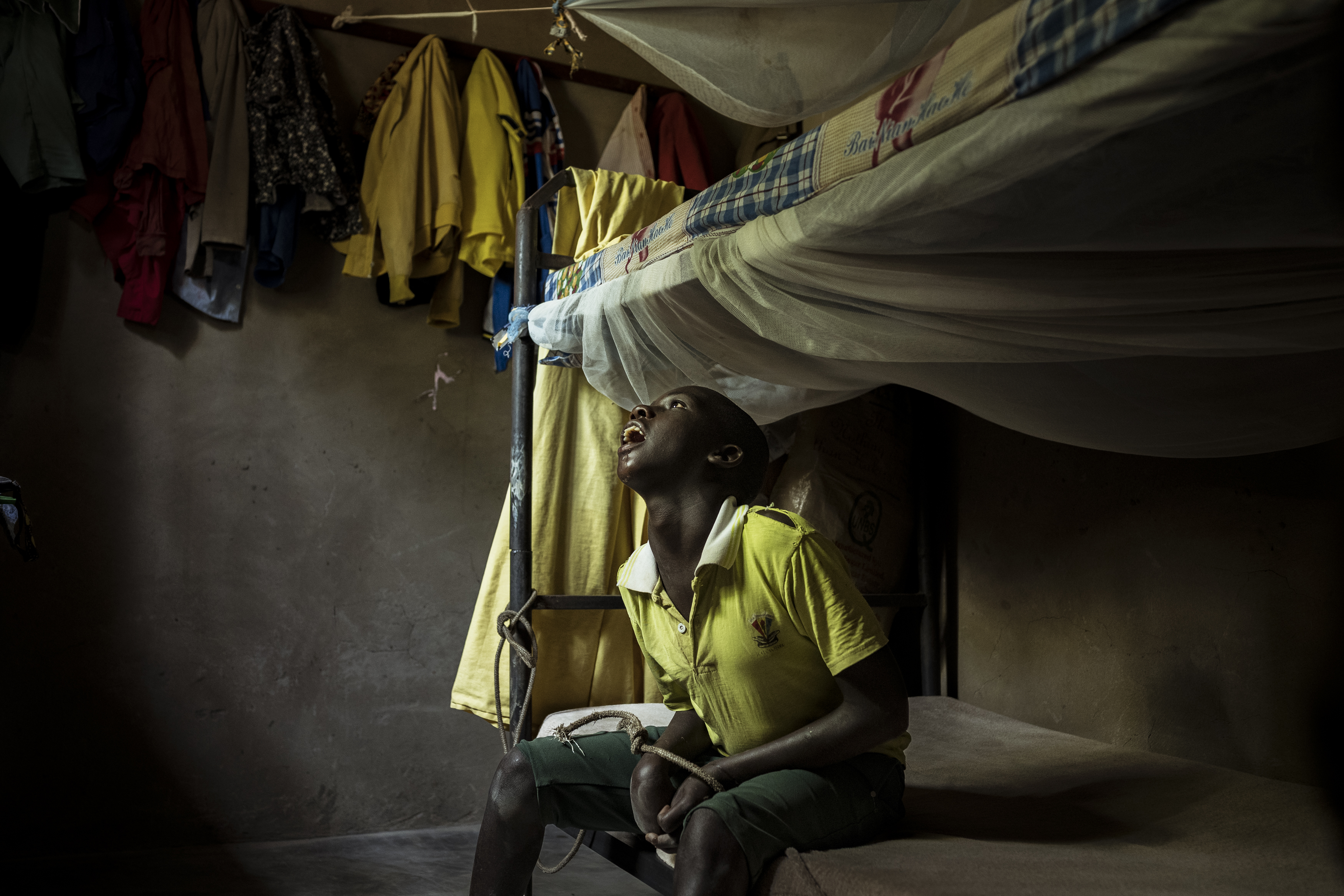 In Omalera, 17-year-old David Emwodu sits with his hands bound by a rope tied to the bunk bed he shares with his brother. David lives with an undiagnosed intellectual disability. He can become violent, especially towards his eldest brother, and when this occurs, his family tethers him to the bed