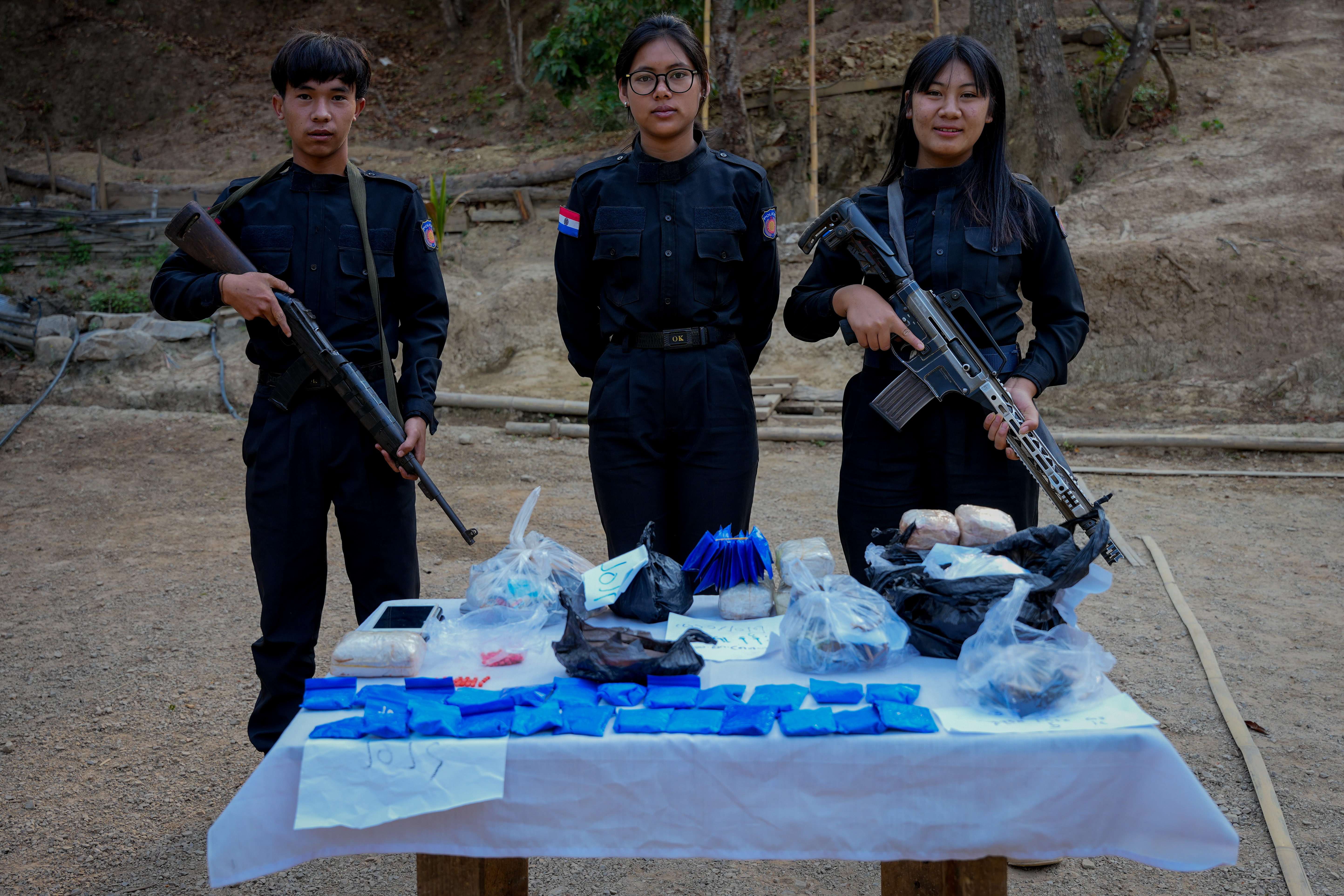 Young Karenni police officers pose in front of a table showing the drugs seized in their checkpoint operations