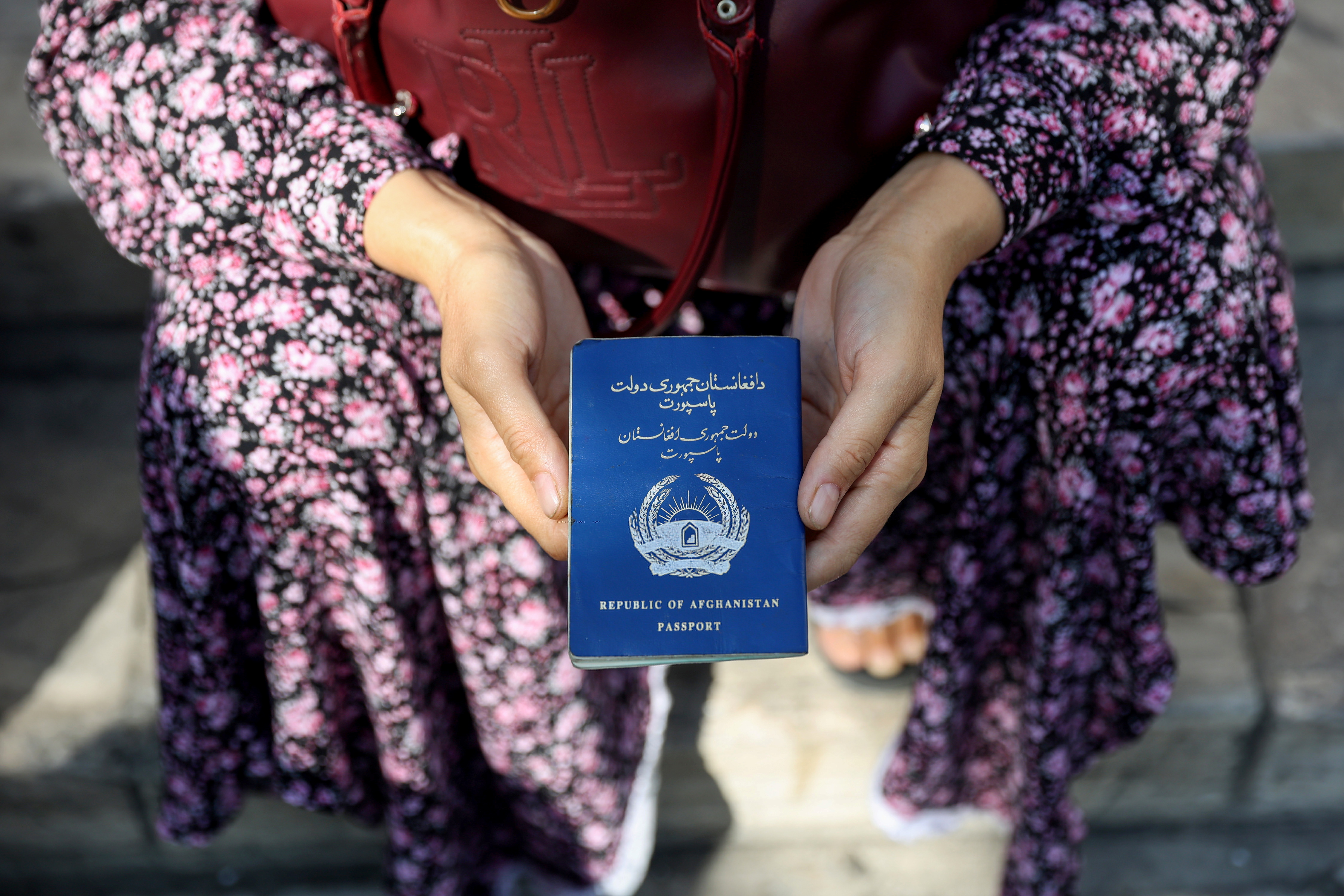 An Afghan refugee holds her passport in front of the German Embassy ​in a bid to acquire refugee visas from the European country, in Tehran