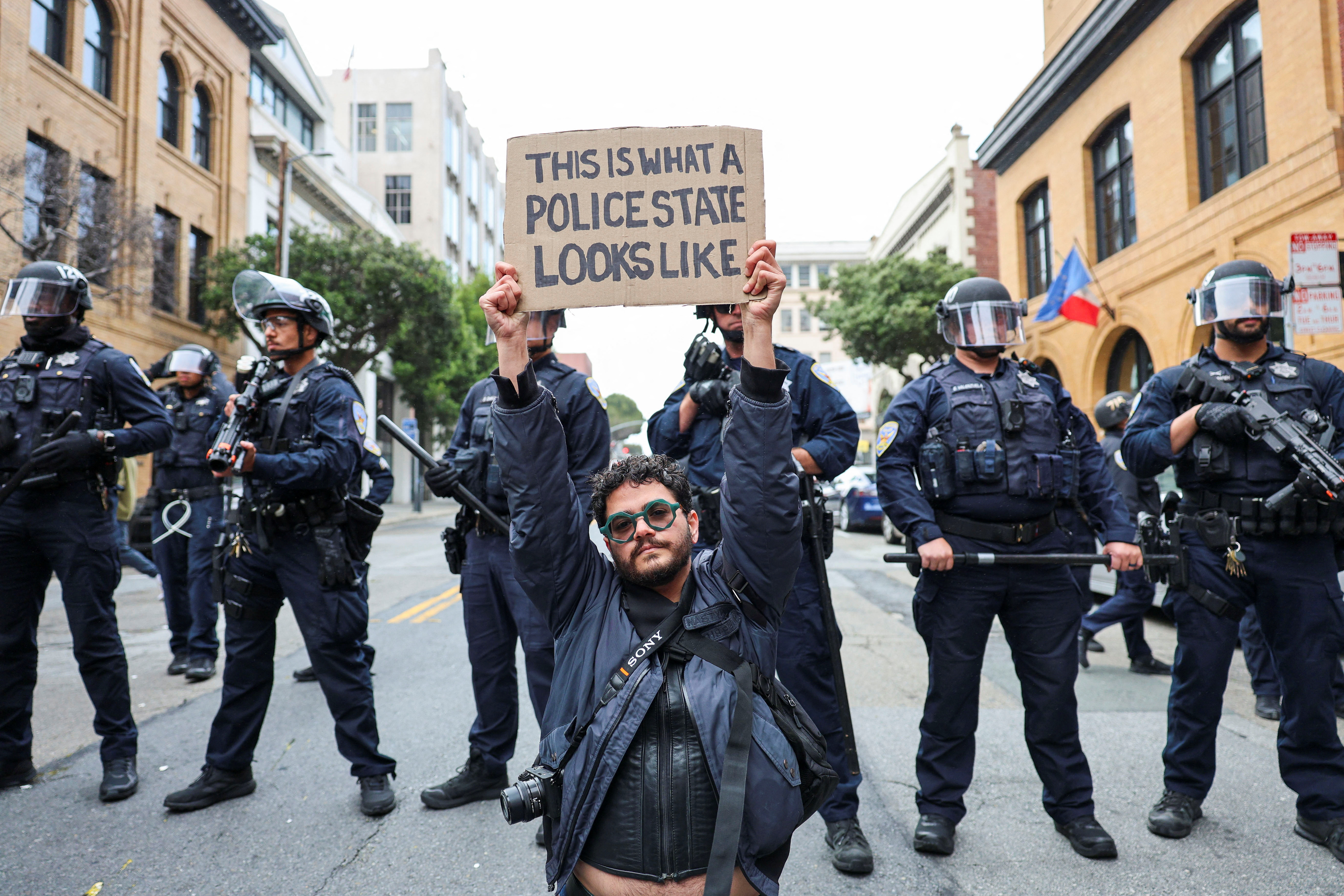 A demonstrator holds up a sign in front of police during a protest against federal immigration sweeps at the ICE building in San Francisco, California, on June 8, 2025