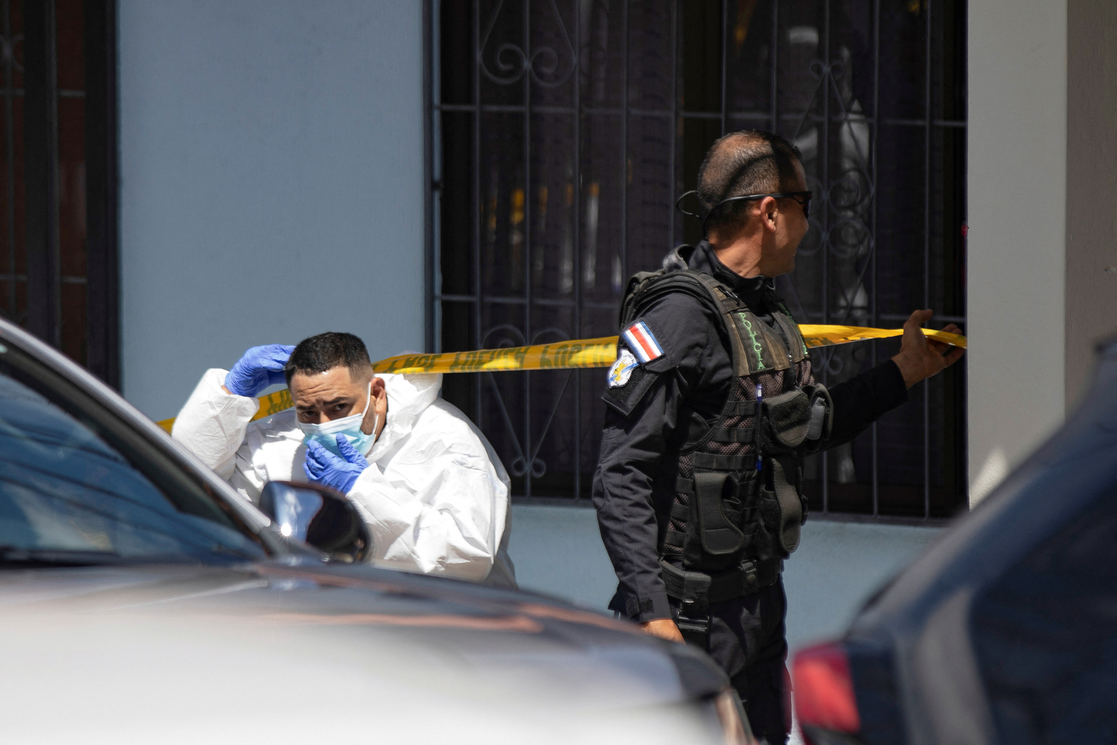A forensic tech ducks under crime scene tape.