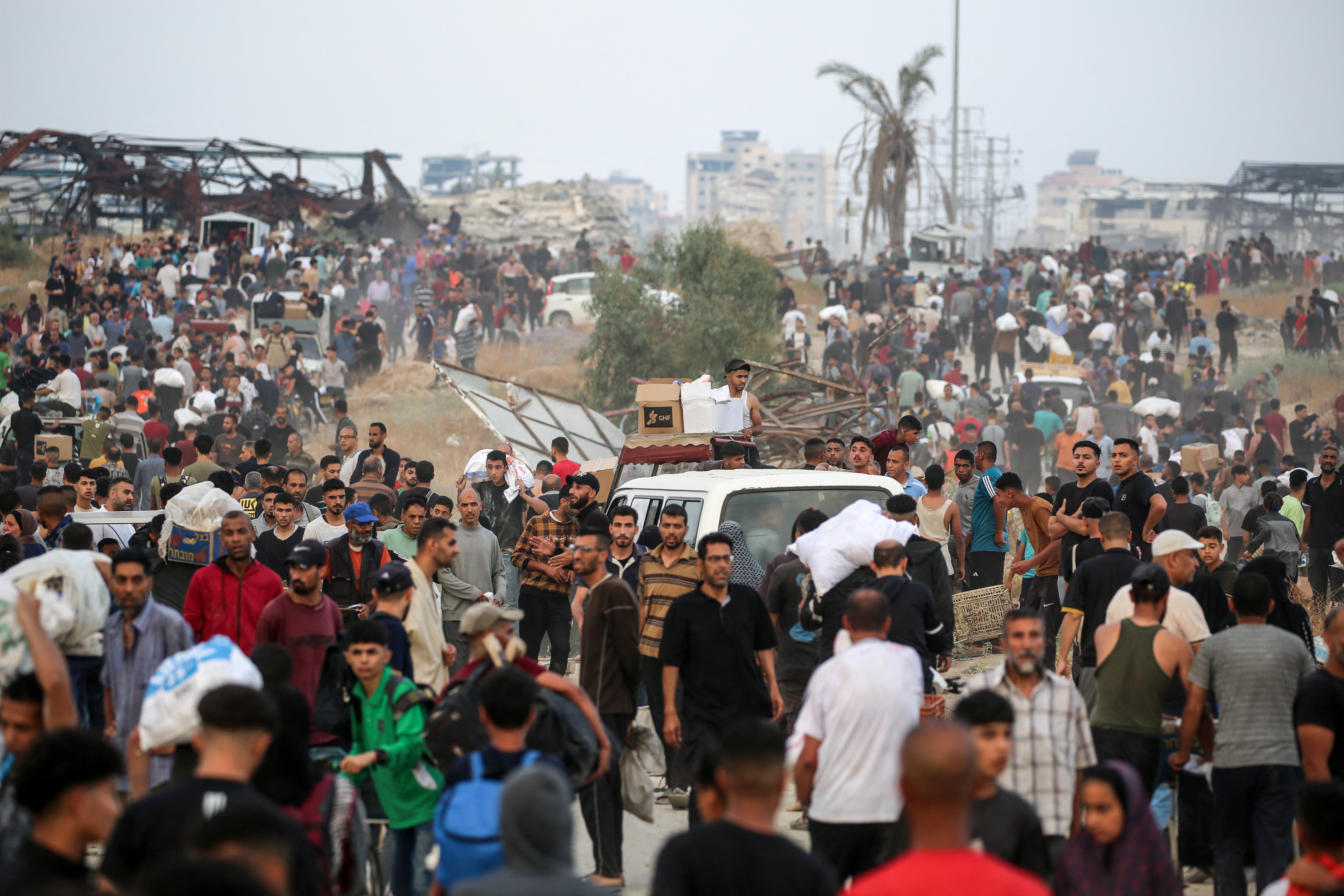 People carry relief supplies on June 8, 2025 after they have been distributed by the Gaza Humanitarian Foundation (GHF), which the United Nations and major aid organisations have refused to cooperate with, citing concerns that GHF was designed to cater to Israeli military objectives