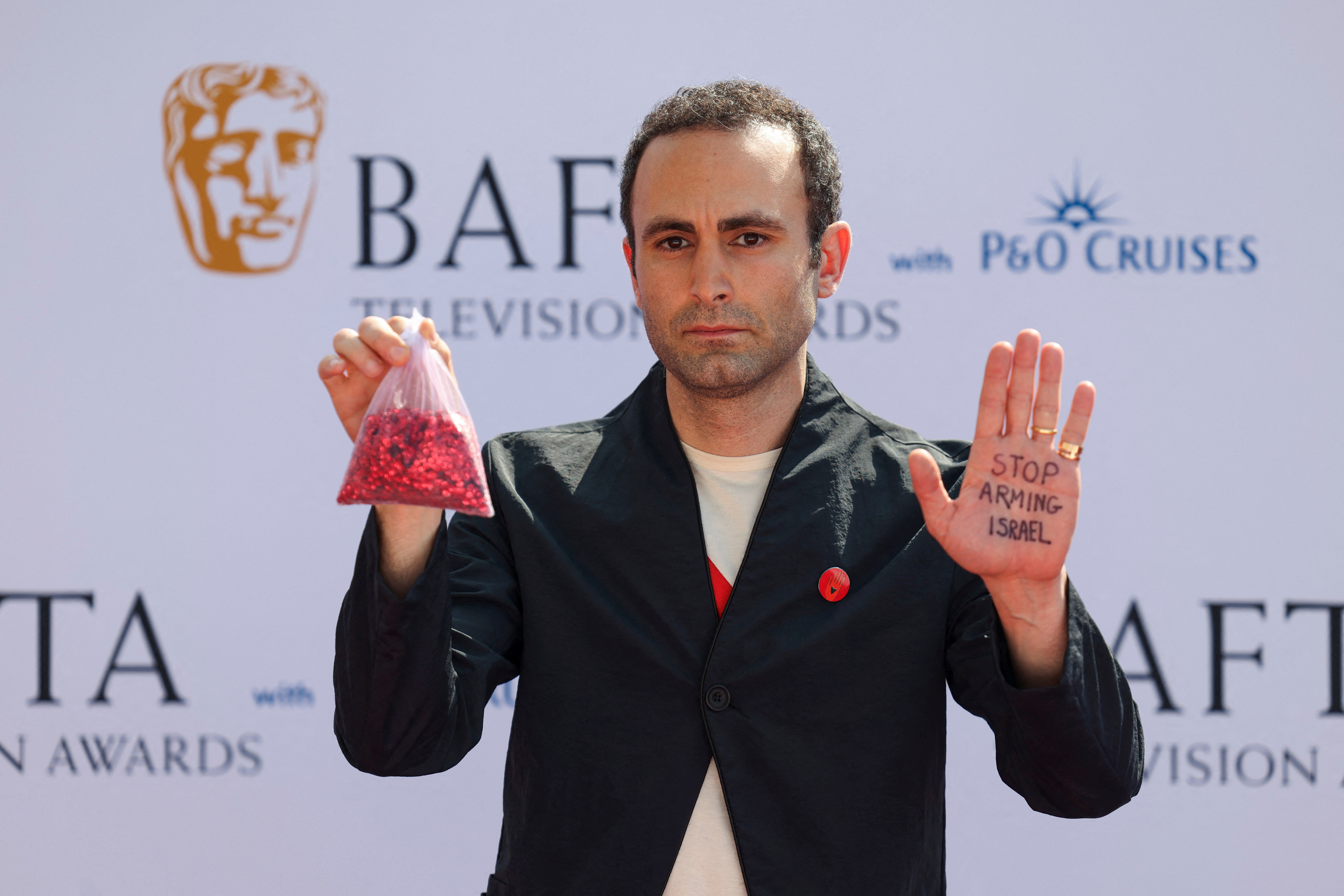 Khalid Abdalla shows a message on his palm as he poses on the red carpet.