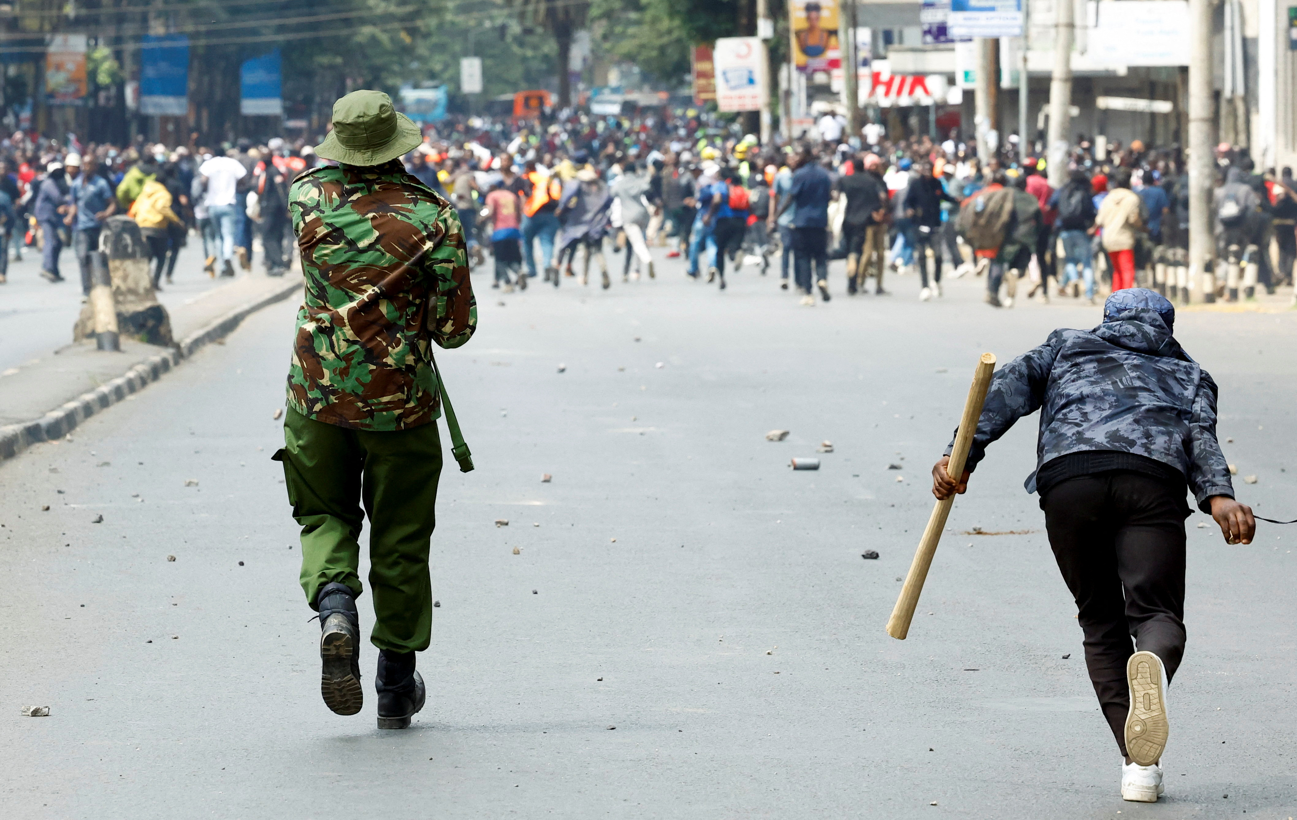 A pro-government counterprotester and a riot police officer rush towards hundreds of protesters angry about state violence