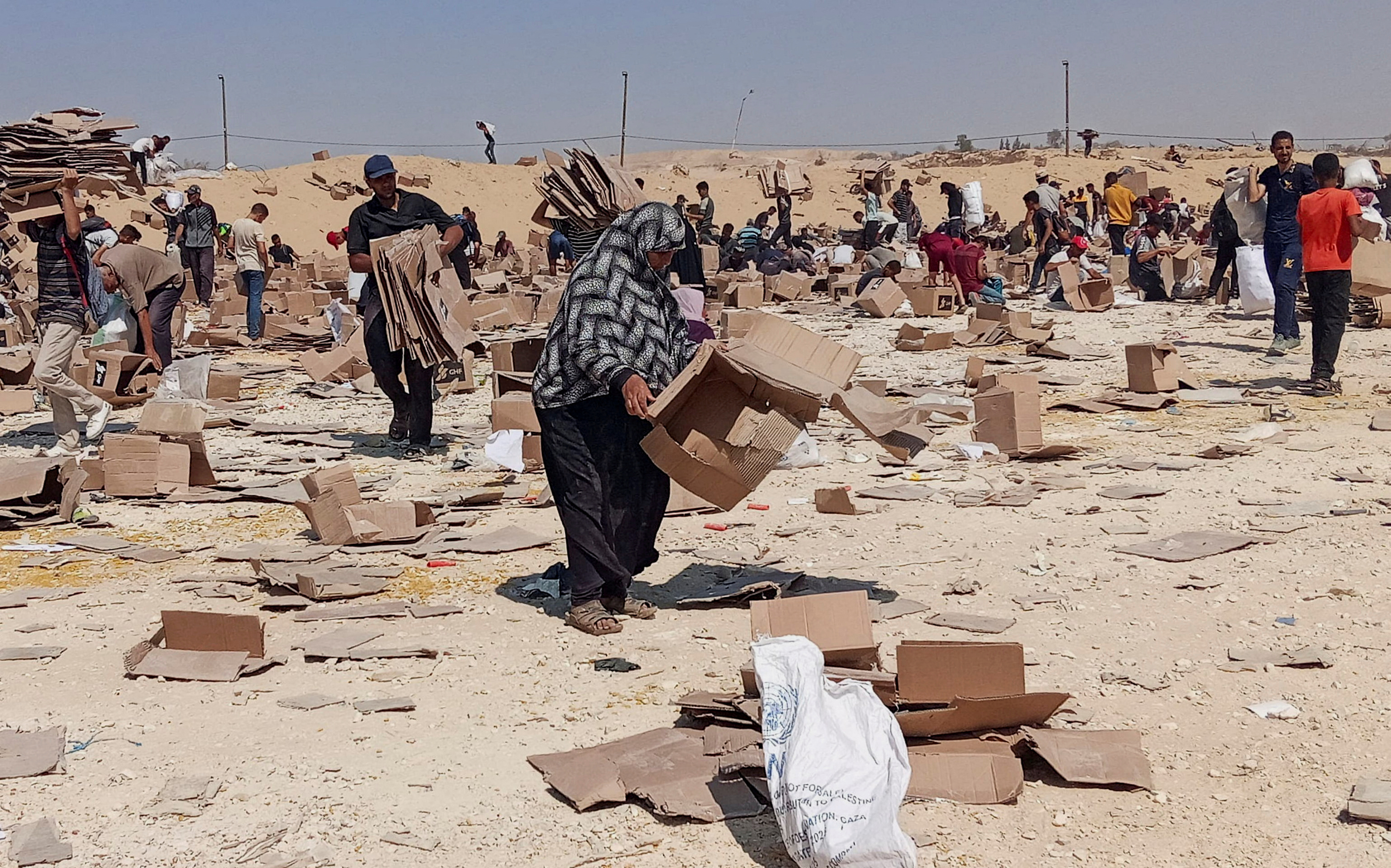 Palestinians gather to collect what remains of relief supplies.
