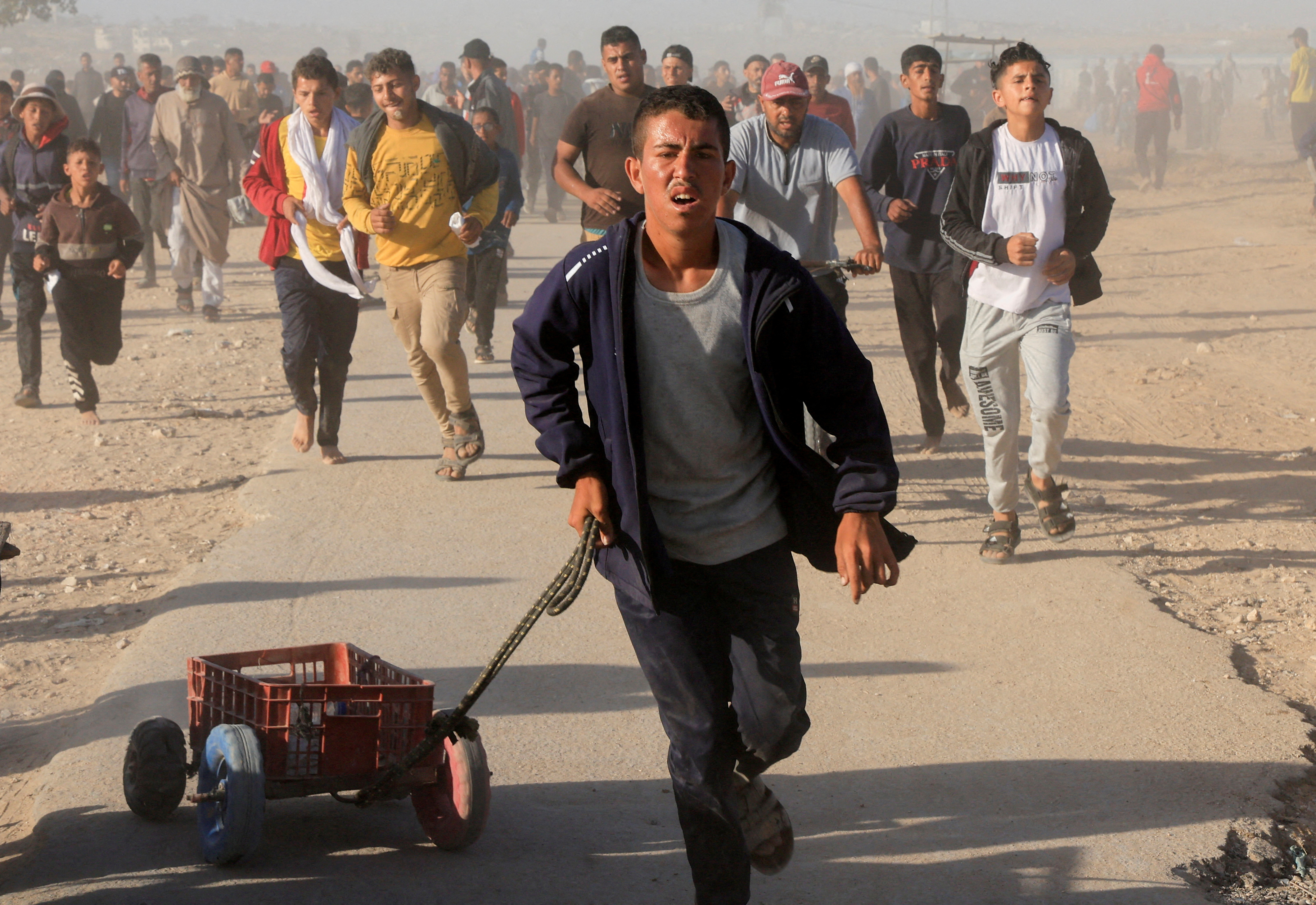 Palestinians walk to collect aid at a Gaza Humanitarian Foundation distribution site