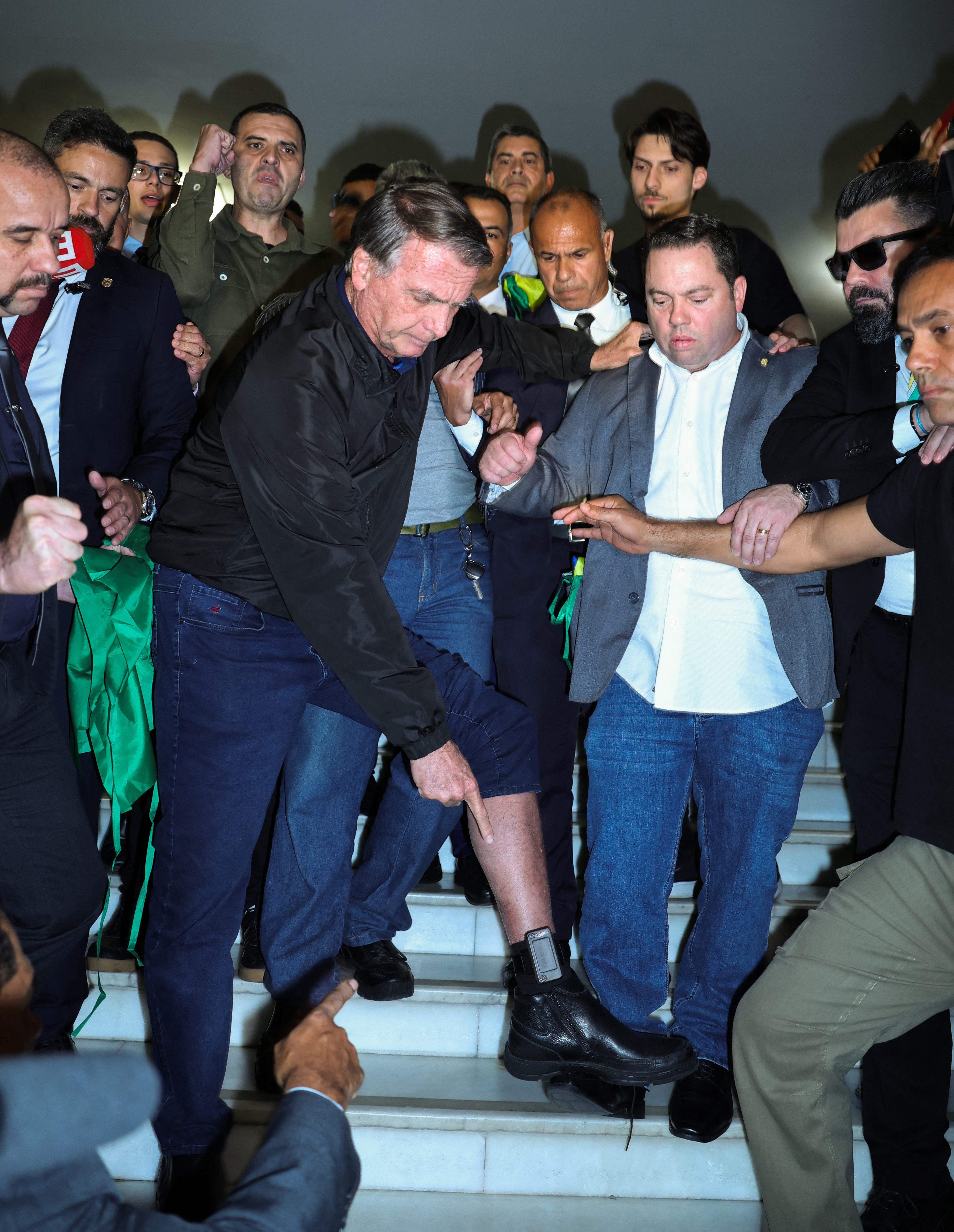 Former Brazilian President Jair Bolsonaro lifts his pant leg to show off his ankle monitor in Brasilia, Brazil, on July 21