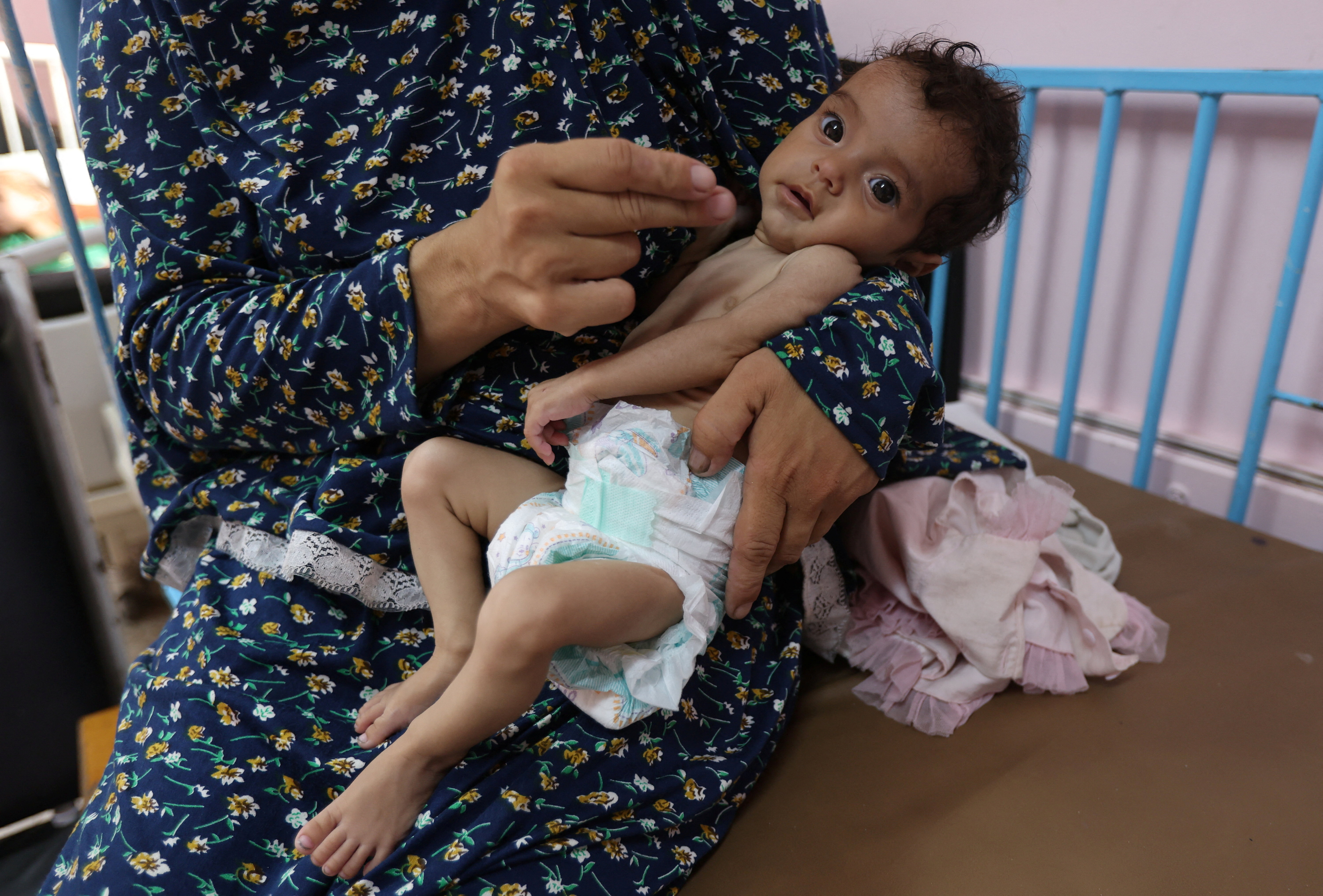 A Palestinian woman holds her 5-month-old daughter, Rama Abu Aya, who is malnourished, according to medics, at Nasser Hospital in Khan Younis, in the southern Gaza Strip, July 24, 2025. [Ramadan Abed/Reuter]