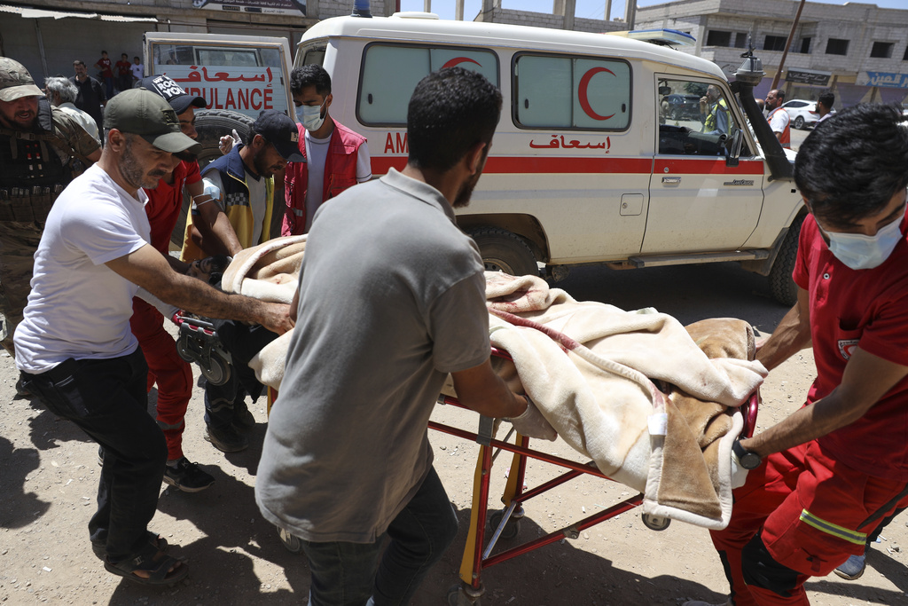 Red Crescent volunteers carry a government soldier injured in Suwayda, Syria, during clashes between government forces and Druze groups on Tuesday