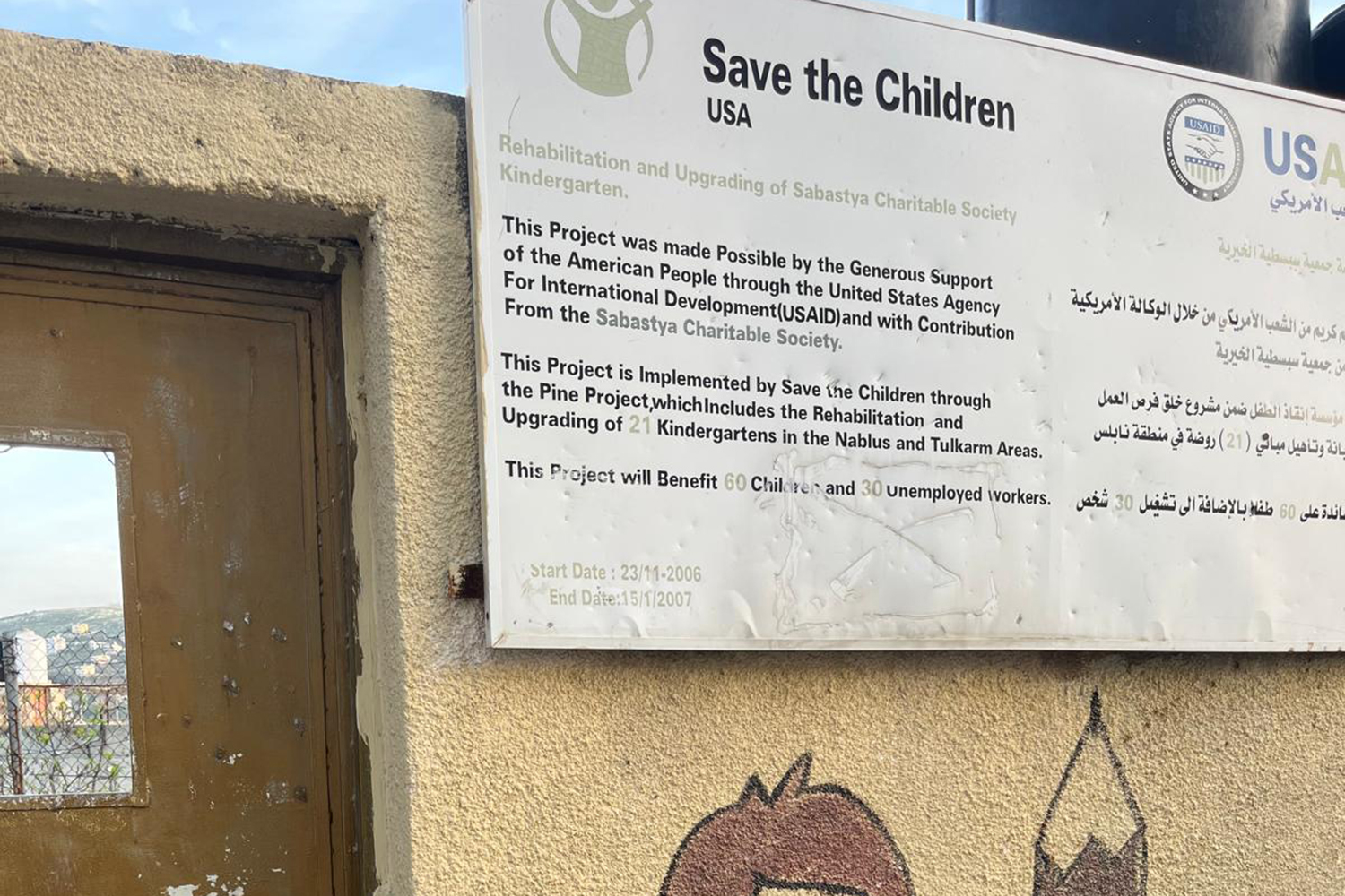 The Save The Children nursery sign, riddled with bullets [Al Jazeera]