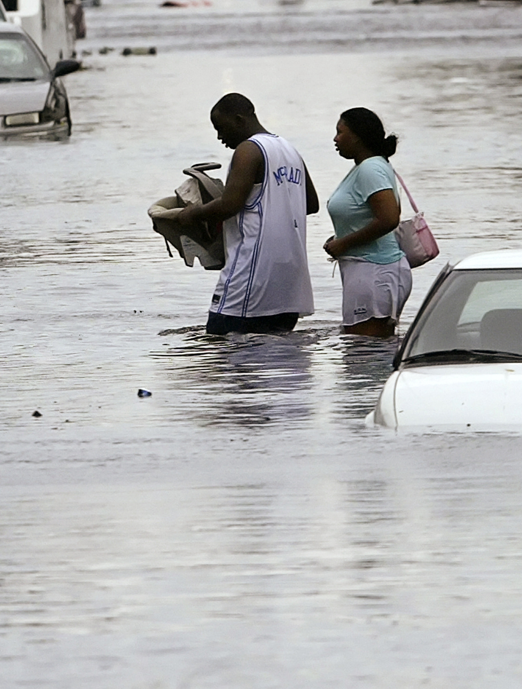 A man carries a baby through flood waters, as the woman behind him abandons their car, in the Treme area of New Orleans, which lies under several feet of water after Hurricane Katrina hit August 29, 2005. Hurricane Katrina ripped into the U.S. Gulf Coast on Monday, battering the historic jazz city New Orleans, swamping resort towns and lowlands with a crushing surge of seawater and stranding people on rooftops. REUTERS/Rick Wilking RTW/DH