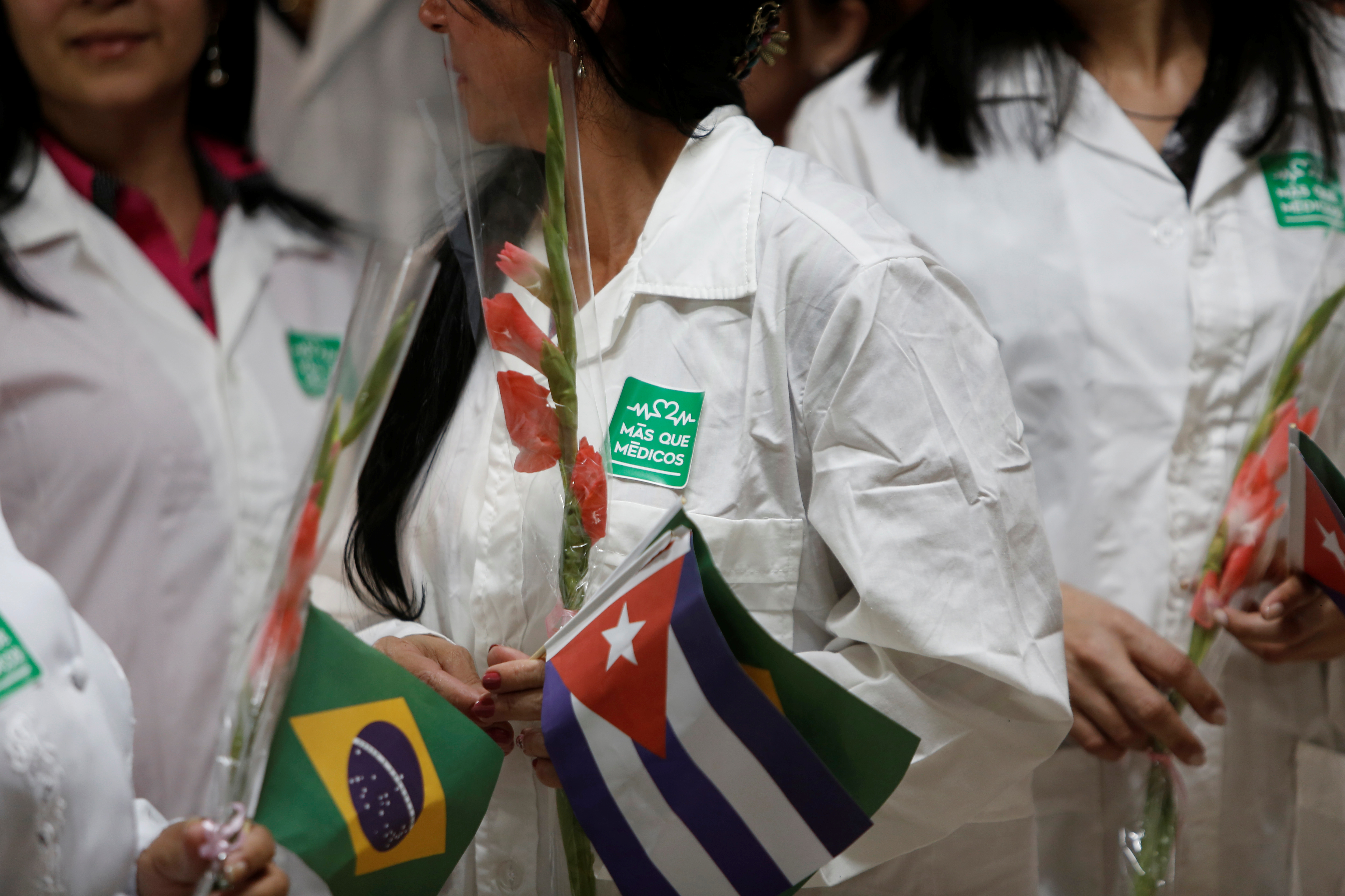 Cuban doctors wear a sticker that reads "More than doctors" during a welcoming ceremony at the Jose Marti International Airport after their arrival from Brazil, in Havana, Cuba, November 23, 2018. REUTERS/Fernando Medina
