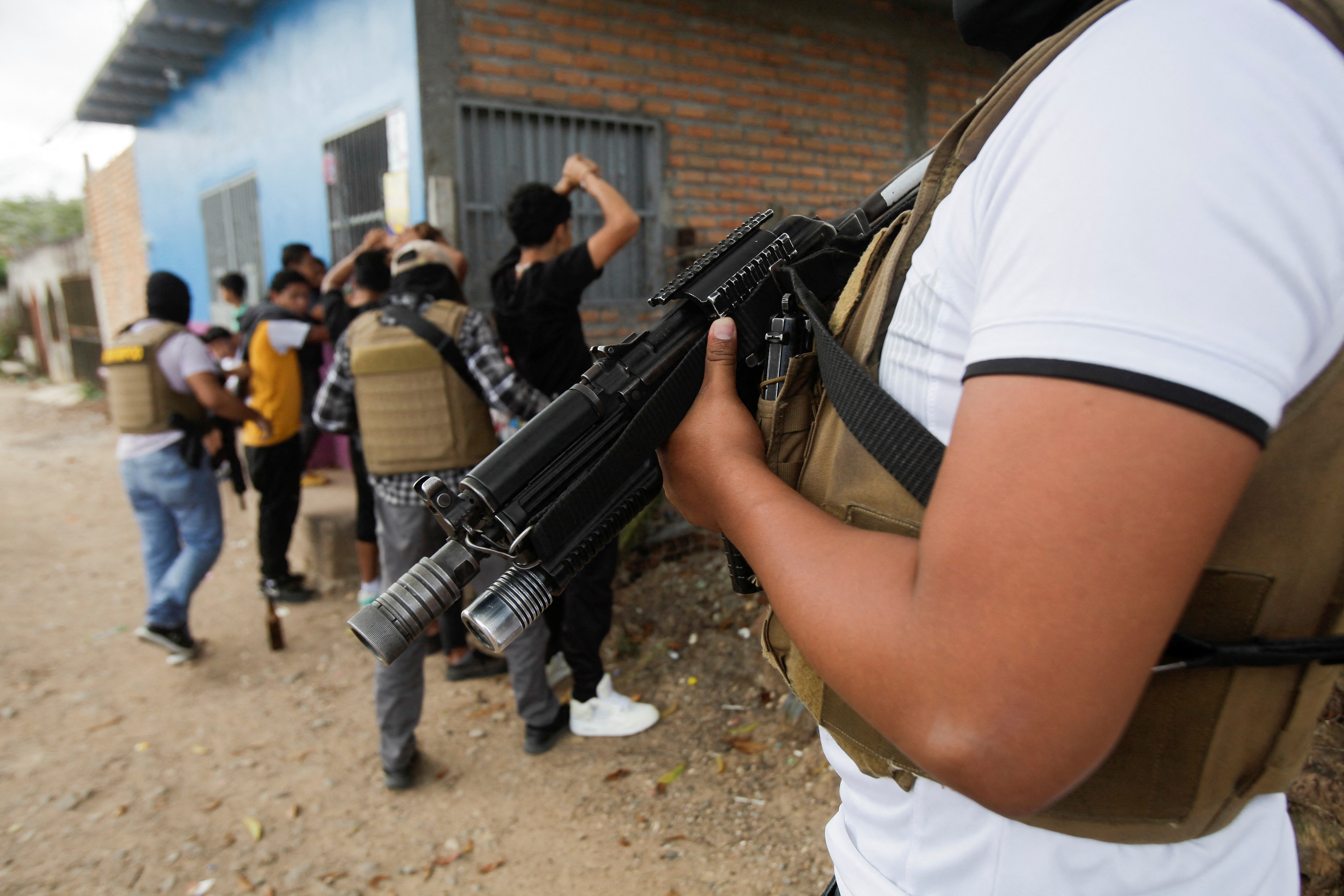 A member of DIPAMPCO police unit holds a gun as his colleagues make an arrest.