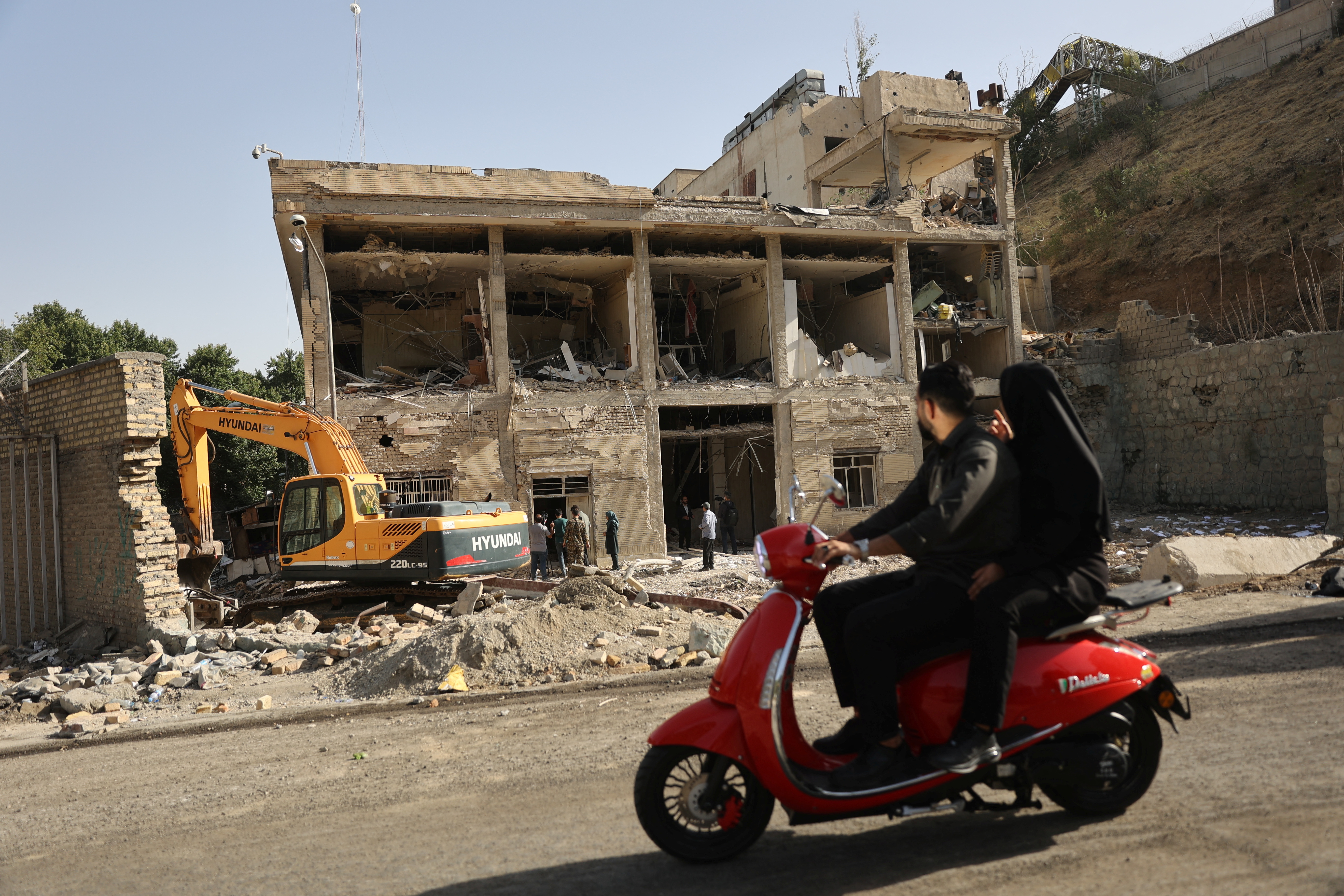 People ride on a motorcycle as a view shows the aftermath of an Israeli strike
