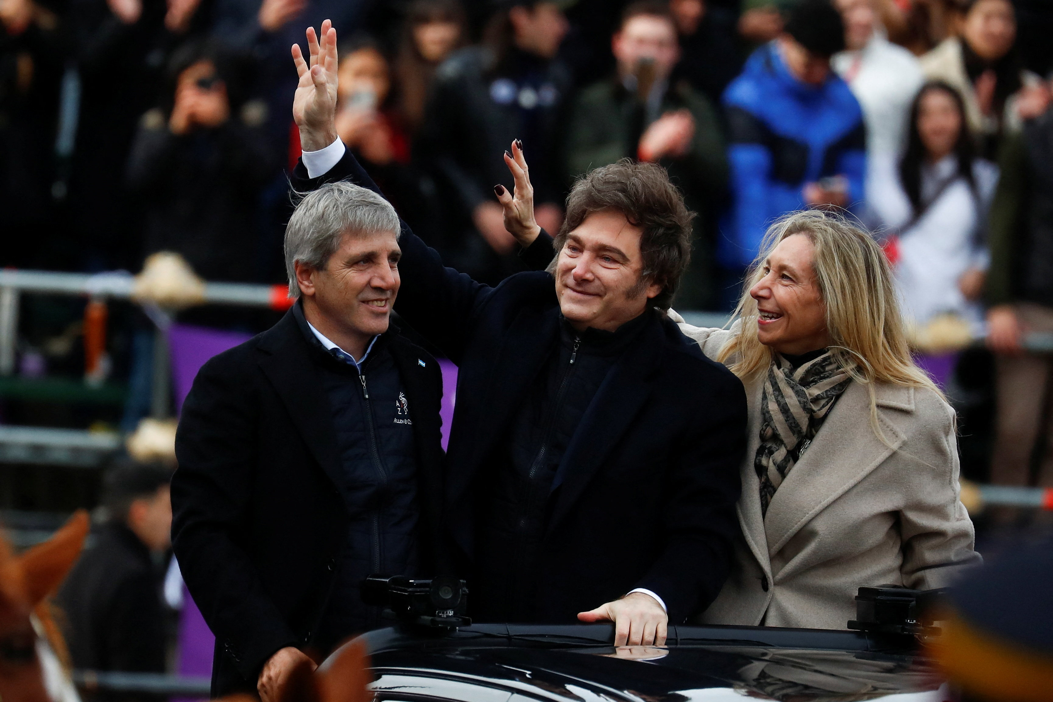 Javier Milei waves as he stands next to Luis Caputo and Karina Milei.