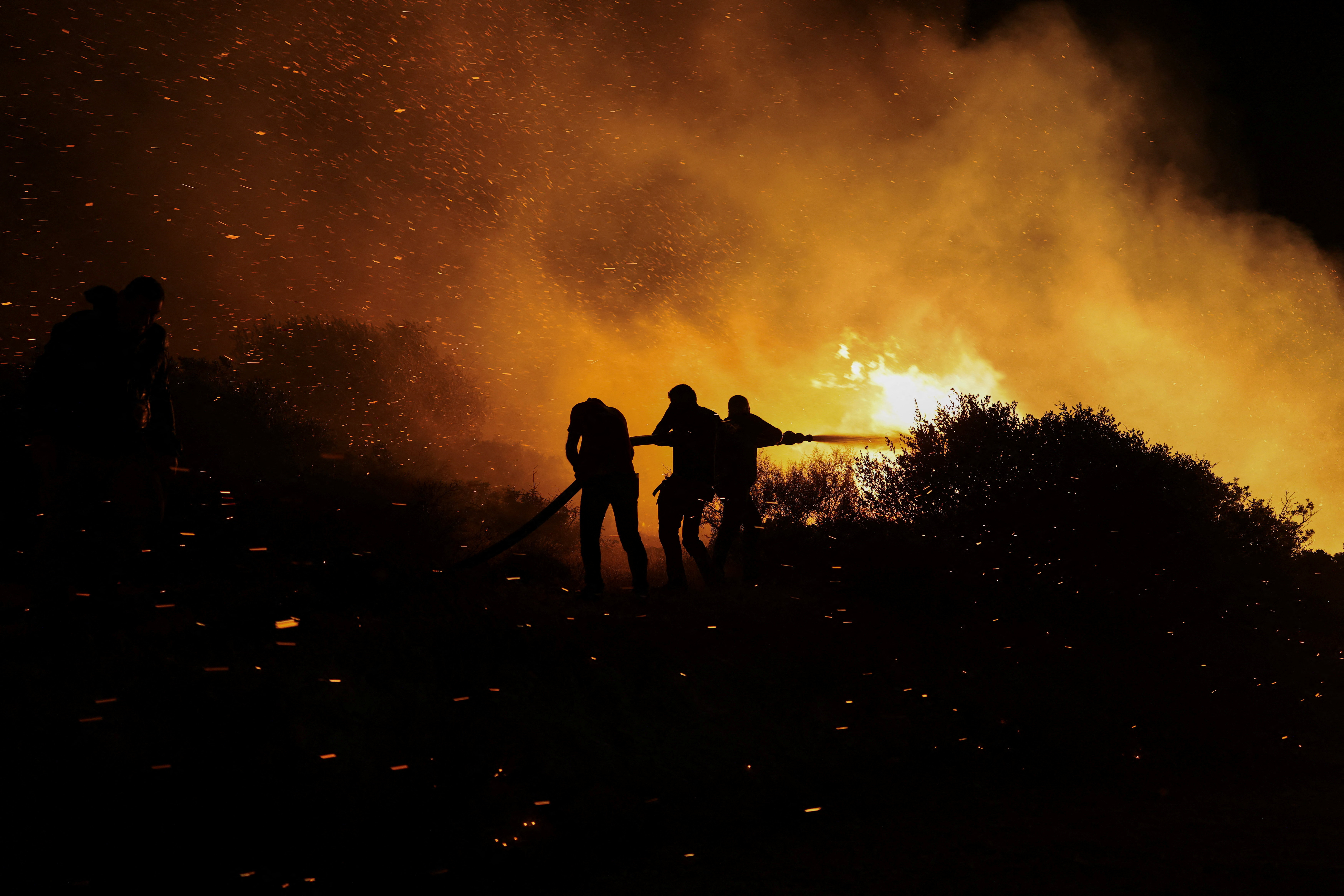 Locals try to extinguish a wildfire burning in Keratea, near Athens, Greece, August 8, 2025. REUTERS/Stelios Misinas