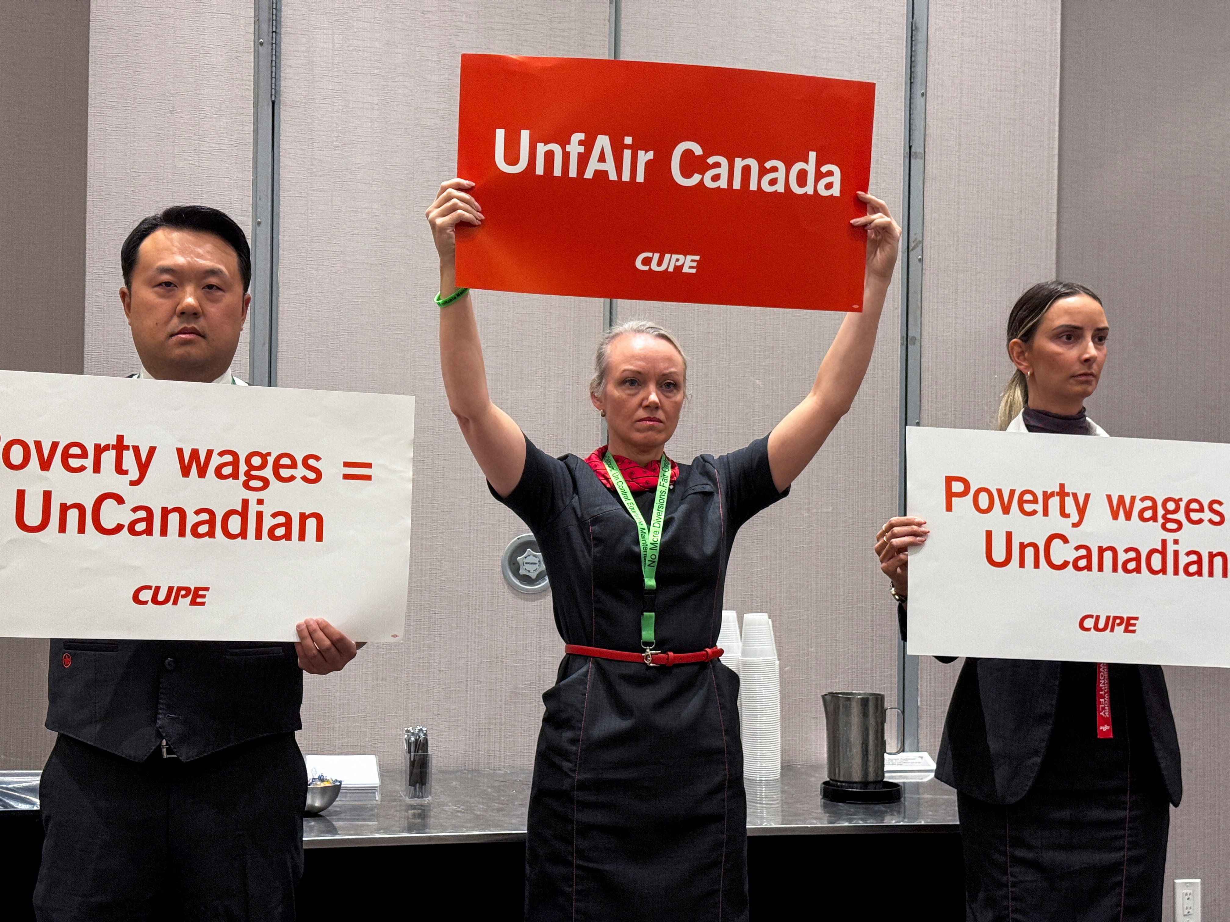 Union activists hold placards as they interrupt a news conference by Air Canada executives on August 14