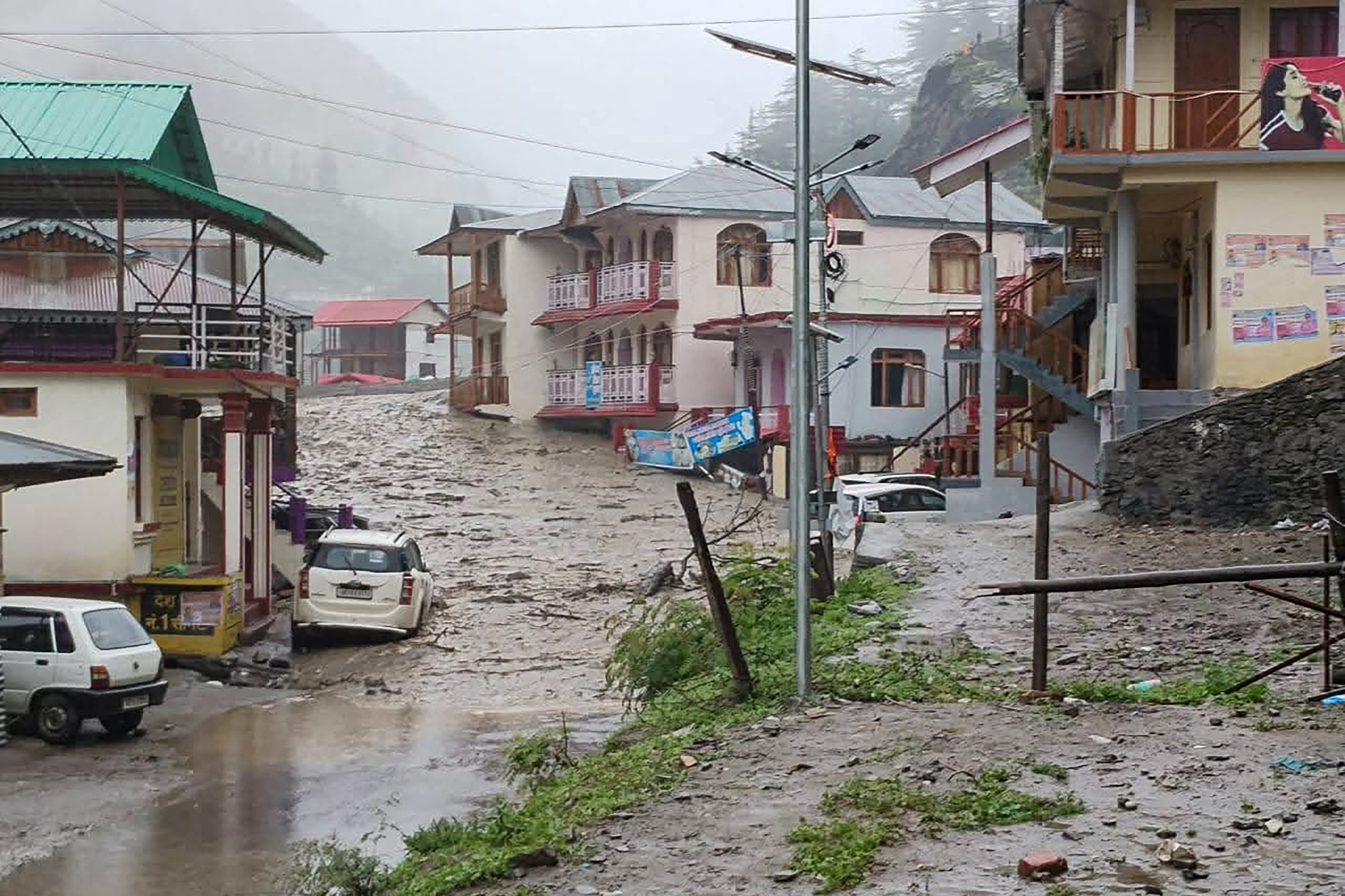 Torrents of muddy water running past residential buildings.