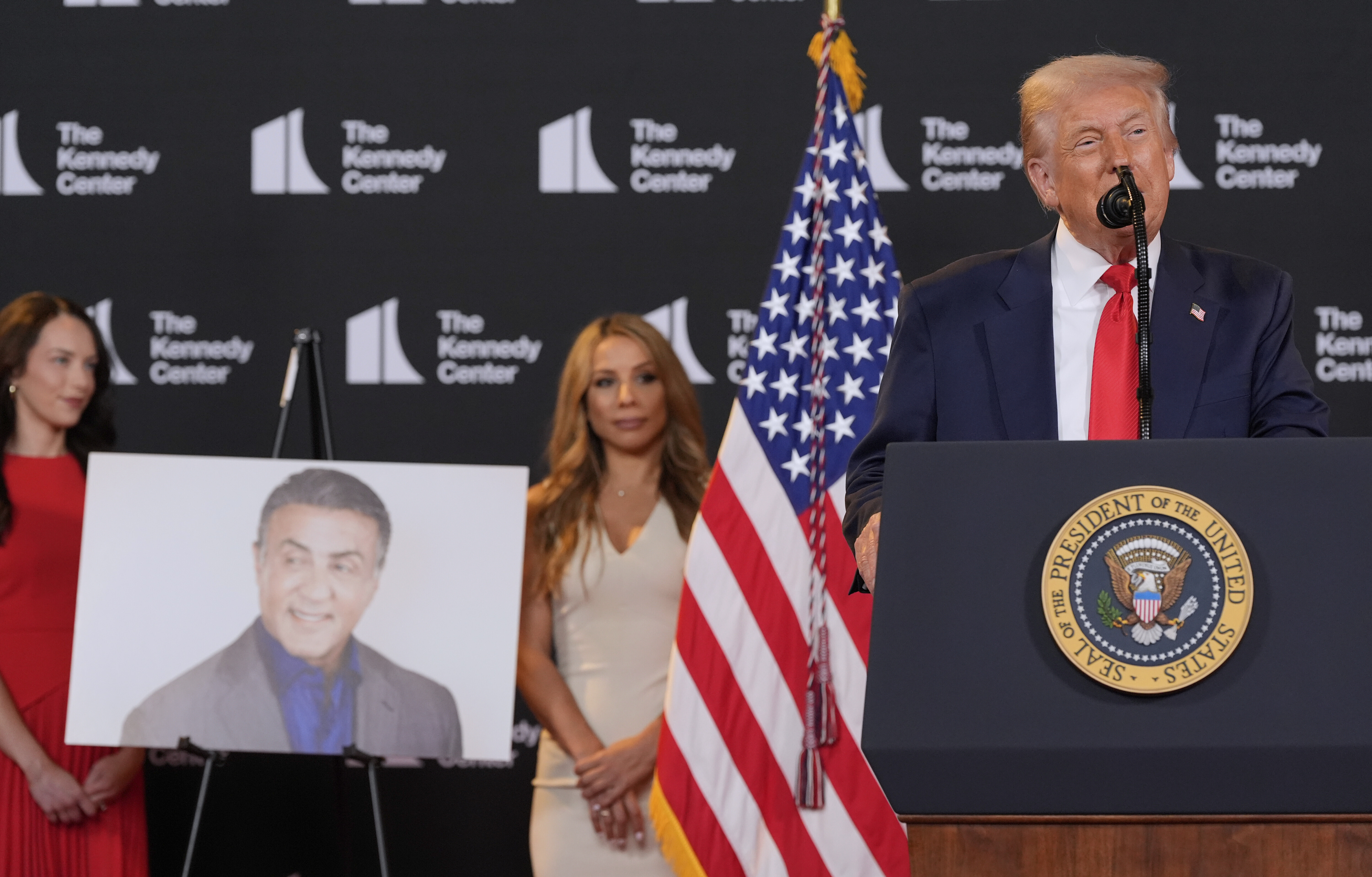 Donald Trump stands in front of a portrait of Sylvester Stallone, a 2025 Kennedy Center honouree