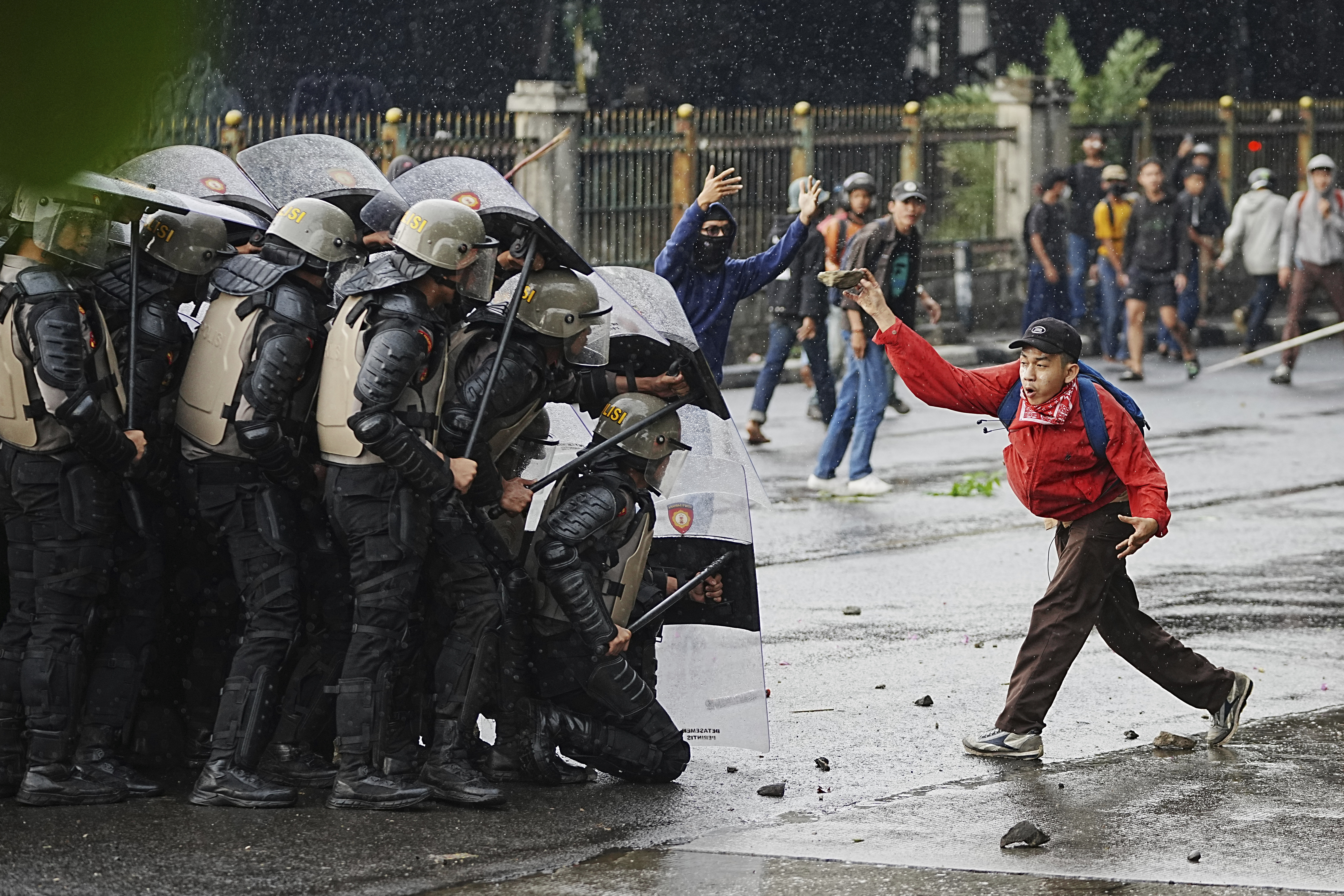 A protester throws a rock at riot police officers during a protest against lavish allowances given to parliament members, in Jakarta, Indonesia, on August 28, 2025