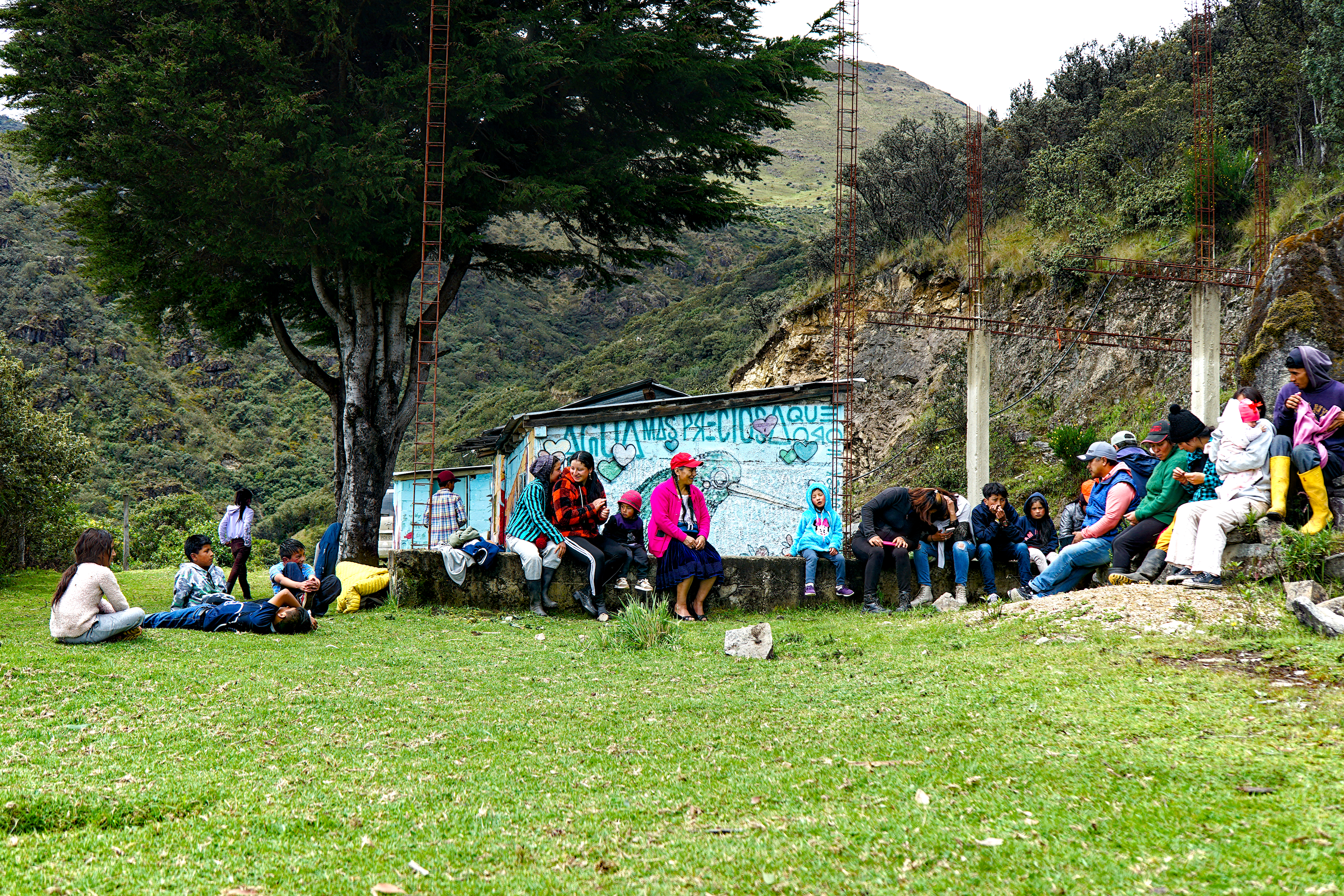 A small group of kids and parents gathers to play in the grass.