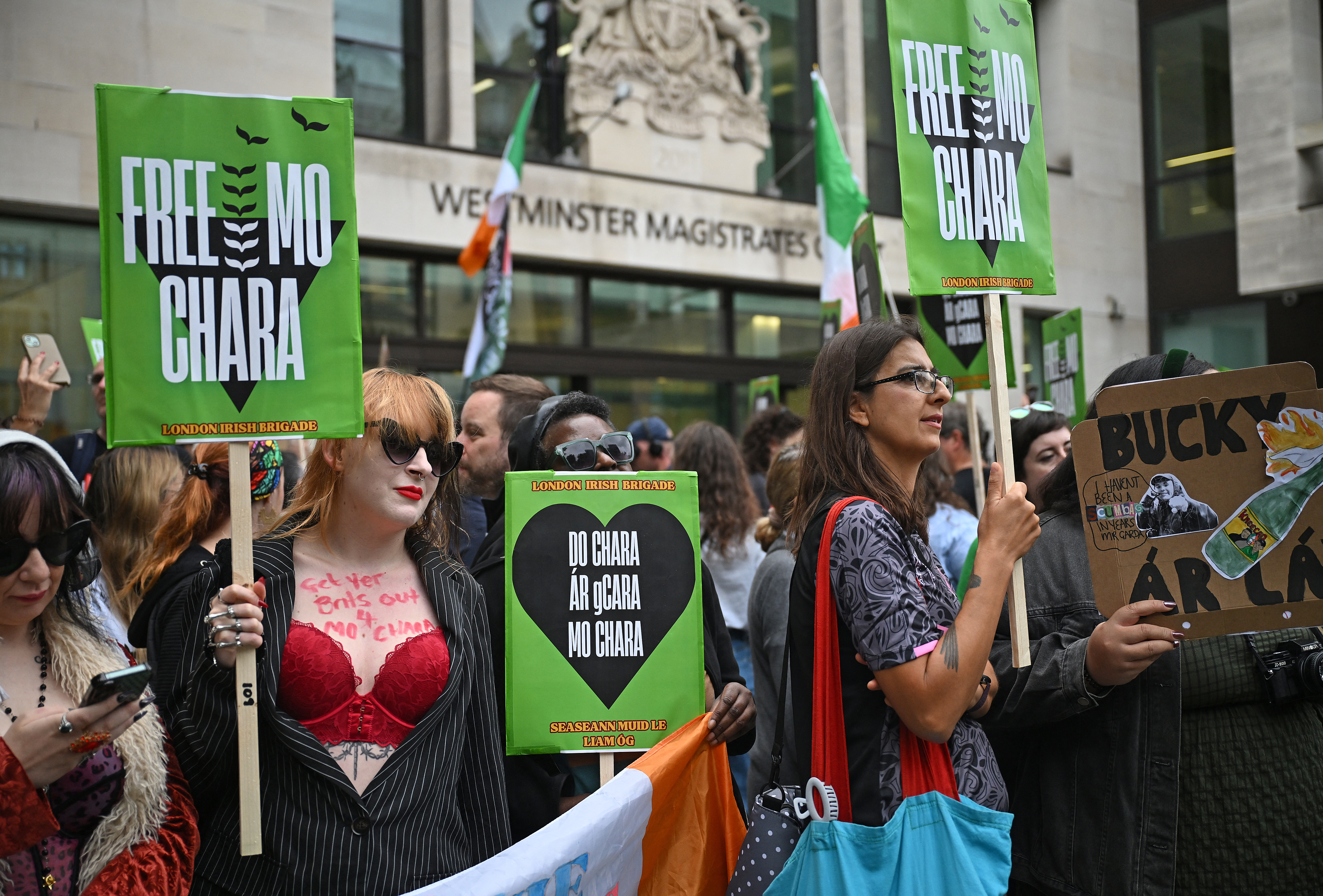 Supporters of the band Kneecap, and its singer Liam O'Hanna who performs under the stage name Mo Chara, hold placards as they gather outside Westminster Magistrates' Courts in London on August 20, 2025, where he is set to appear charged with a terror offence.