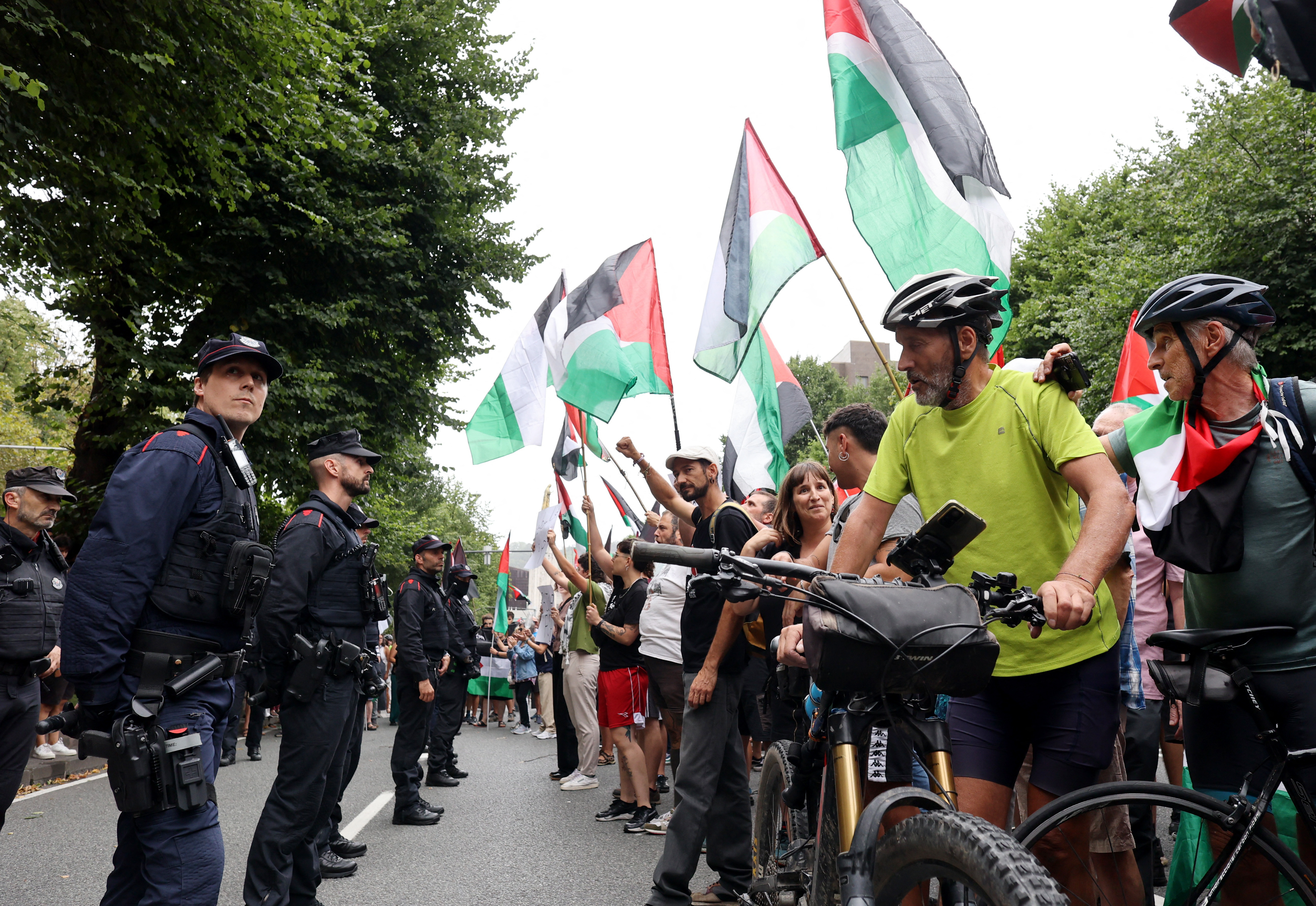 Police office look on at protesters with the flag of Palestine during stage 11 of Vuelta a Espana