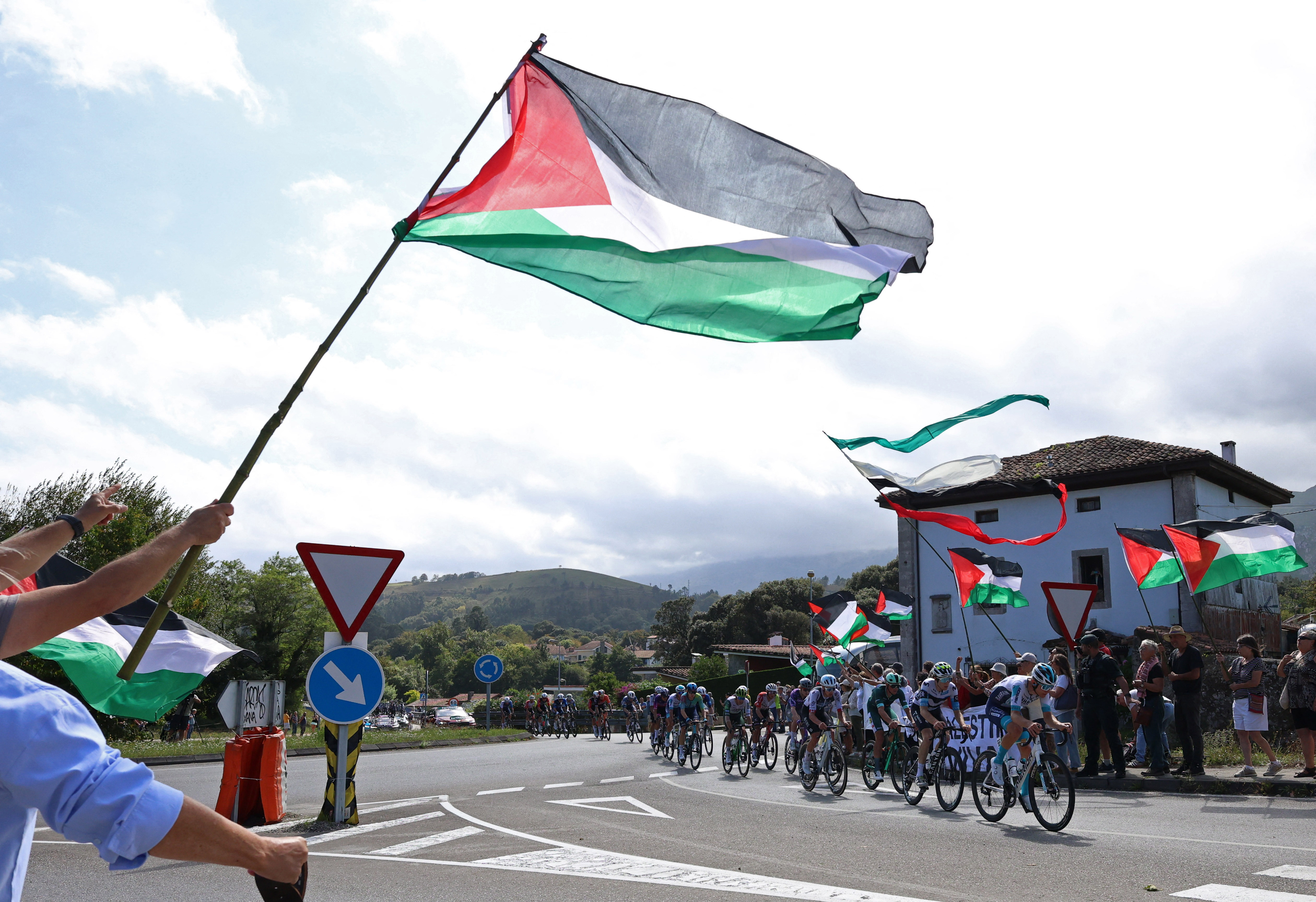 Riders pass protesters with Palestine flags during stage 13 of cycling's Vuelta a Espana