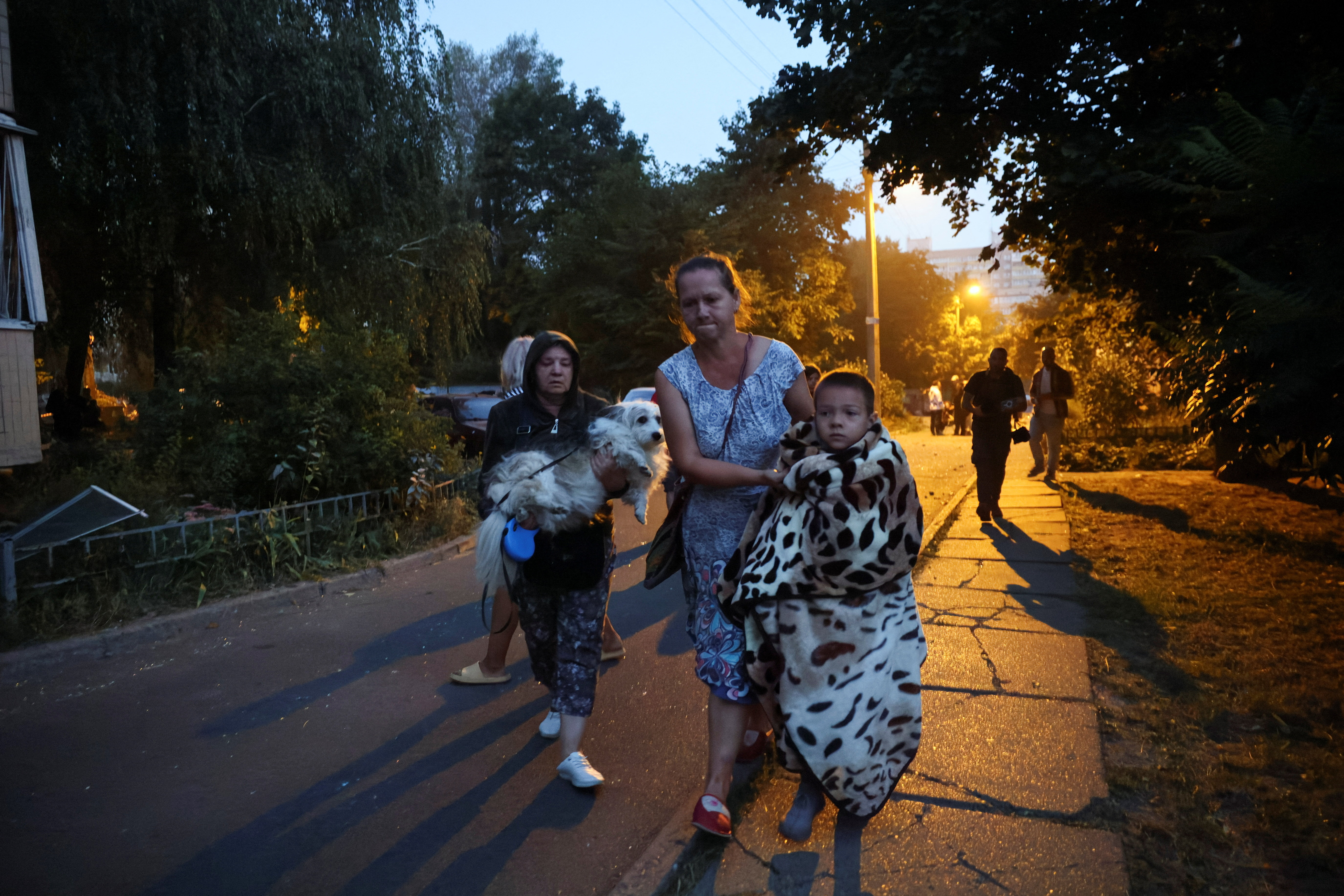 Residents move towards a shelter from their apartment building that was damaged during a Russian drone strike in Kyiv, Ukraine