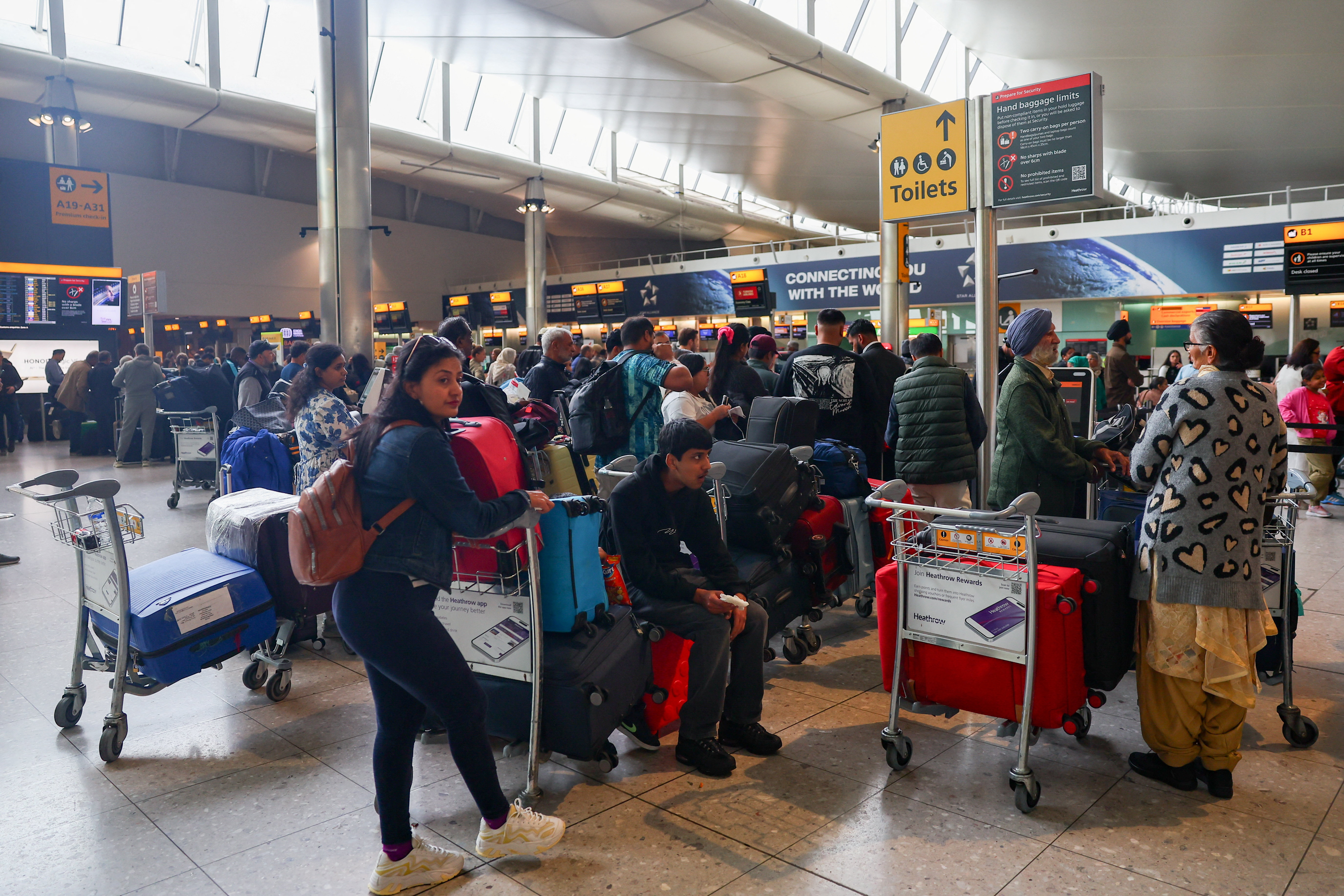 Travellers wait near check-in desks at Heathrow airport in the Greater London area, UK