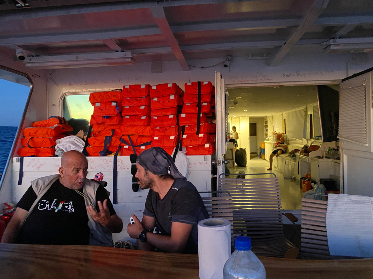 Volunteers talk at the end of the day on board a Flotilla vessel, life vests prepared for any maritime emergency, attack or interception