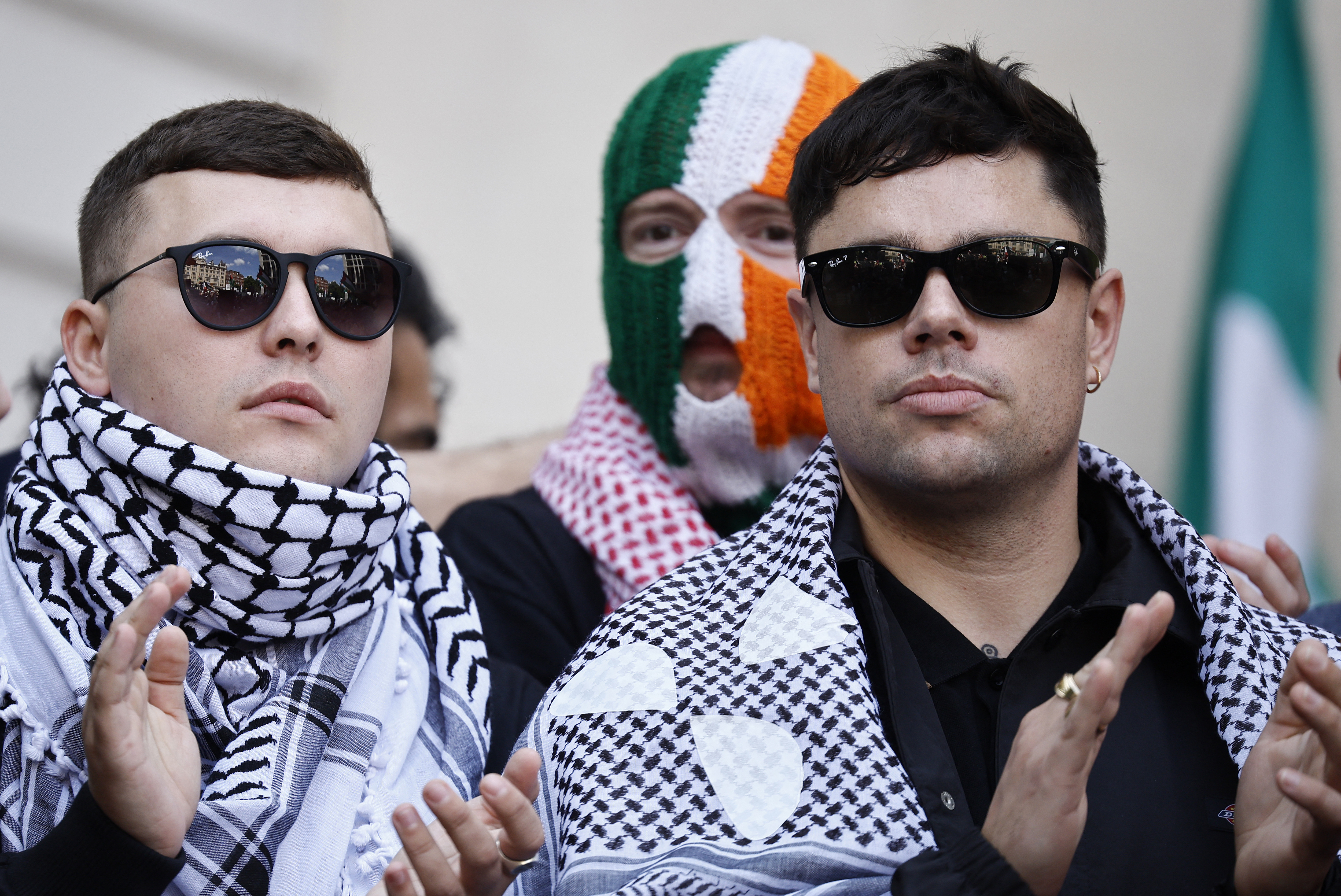 Irish rap group Kneecap singer, Liam O'Hanna (L), who performs under the stage name Mo Chara, stands with band mates Naoise O Caireallain, aka Moglai Bap (R), and JJ O'Dochartaigh, aka DJ Provai (C), outside a court.