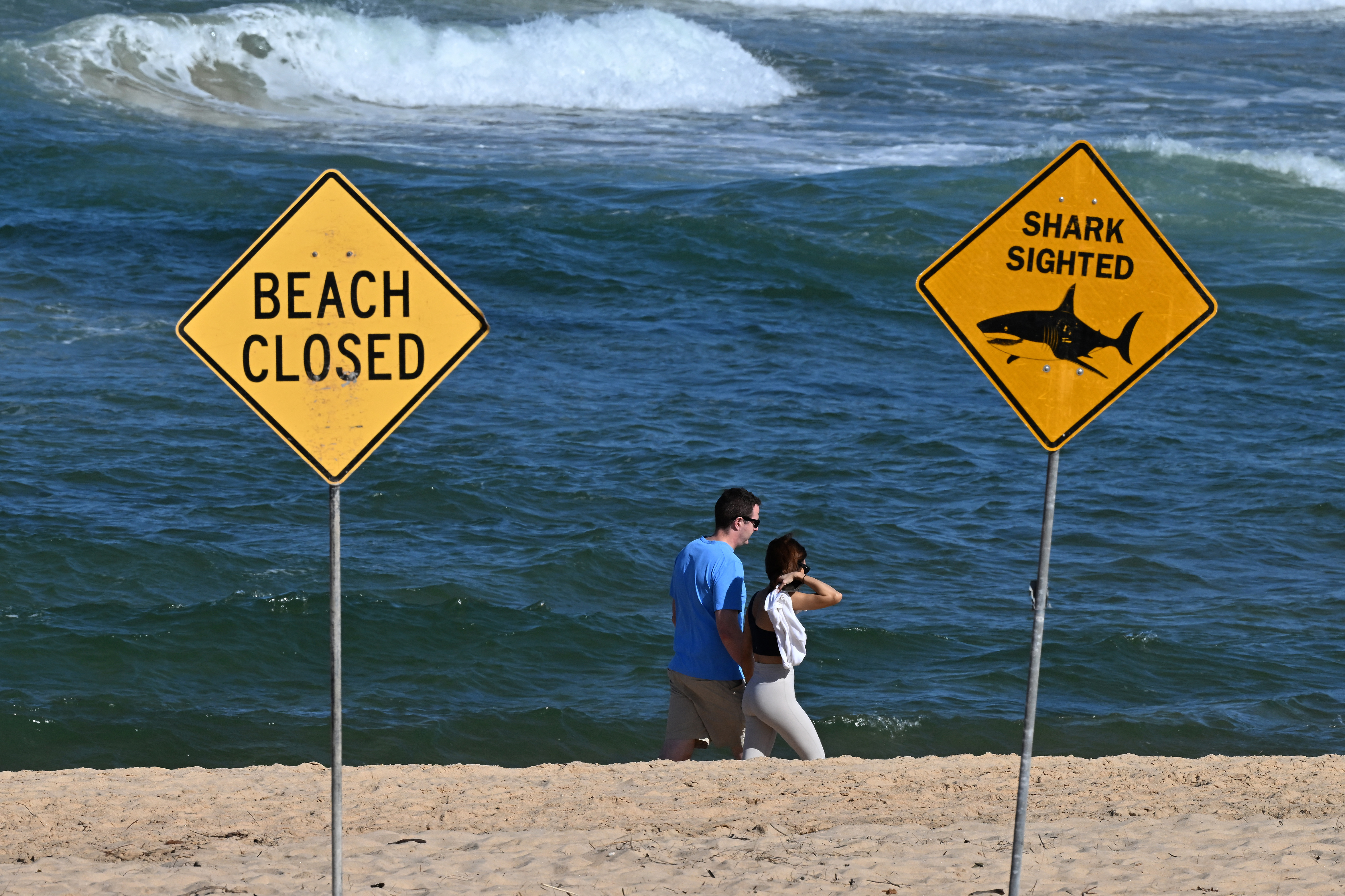 Visitors walk along the shoreline as northern Sydney beaches remain closed.