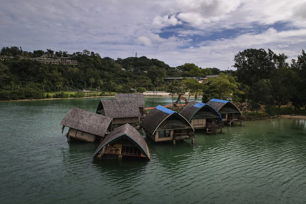 thatched villas are seen in green ocean water