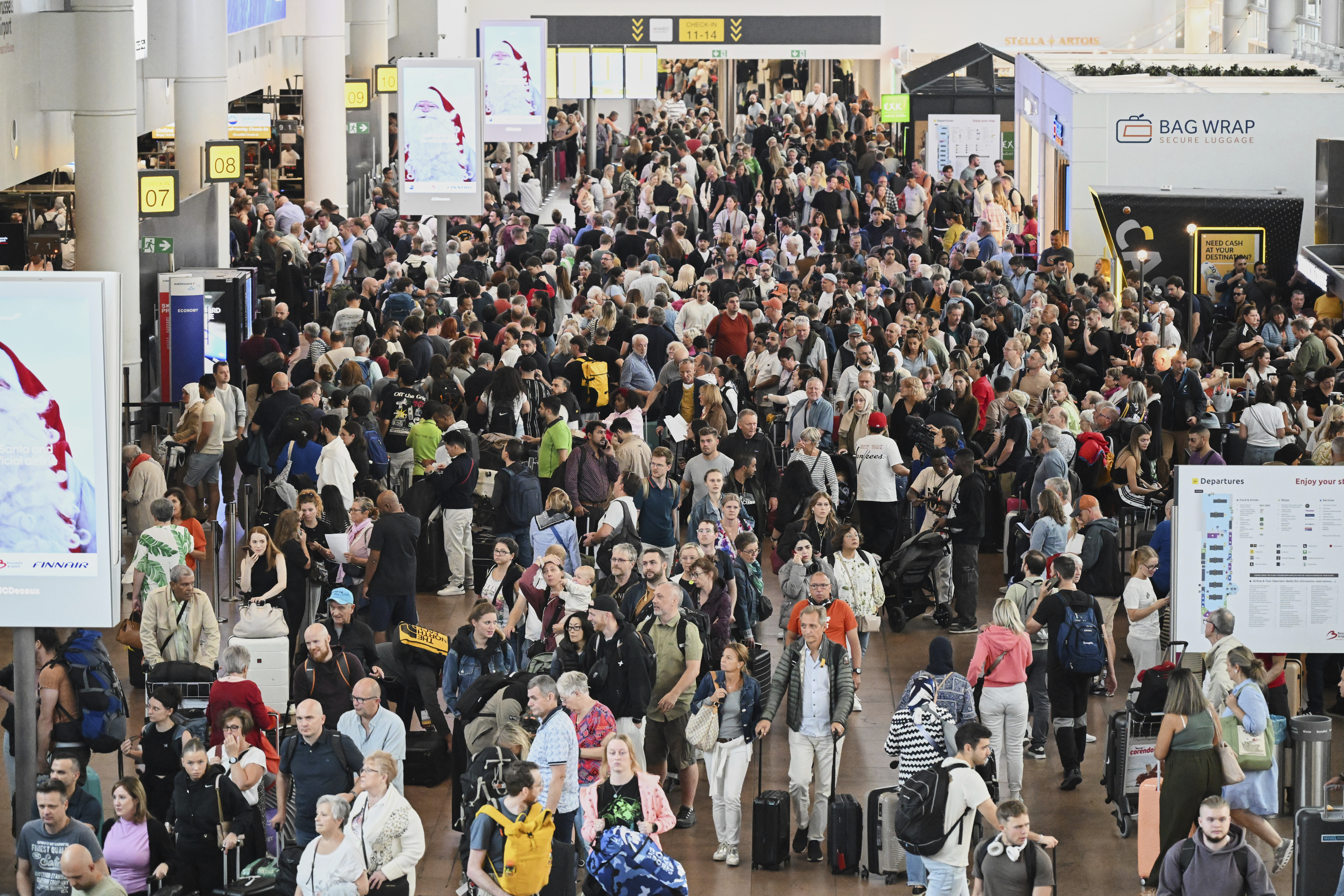 People walk by a departures board at Brussels airport in Zaventem, Belgium