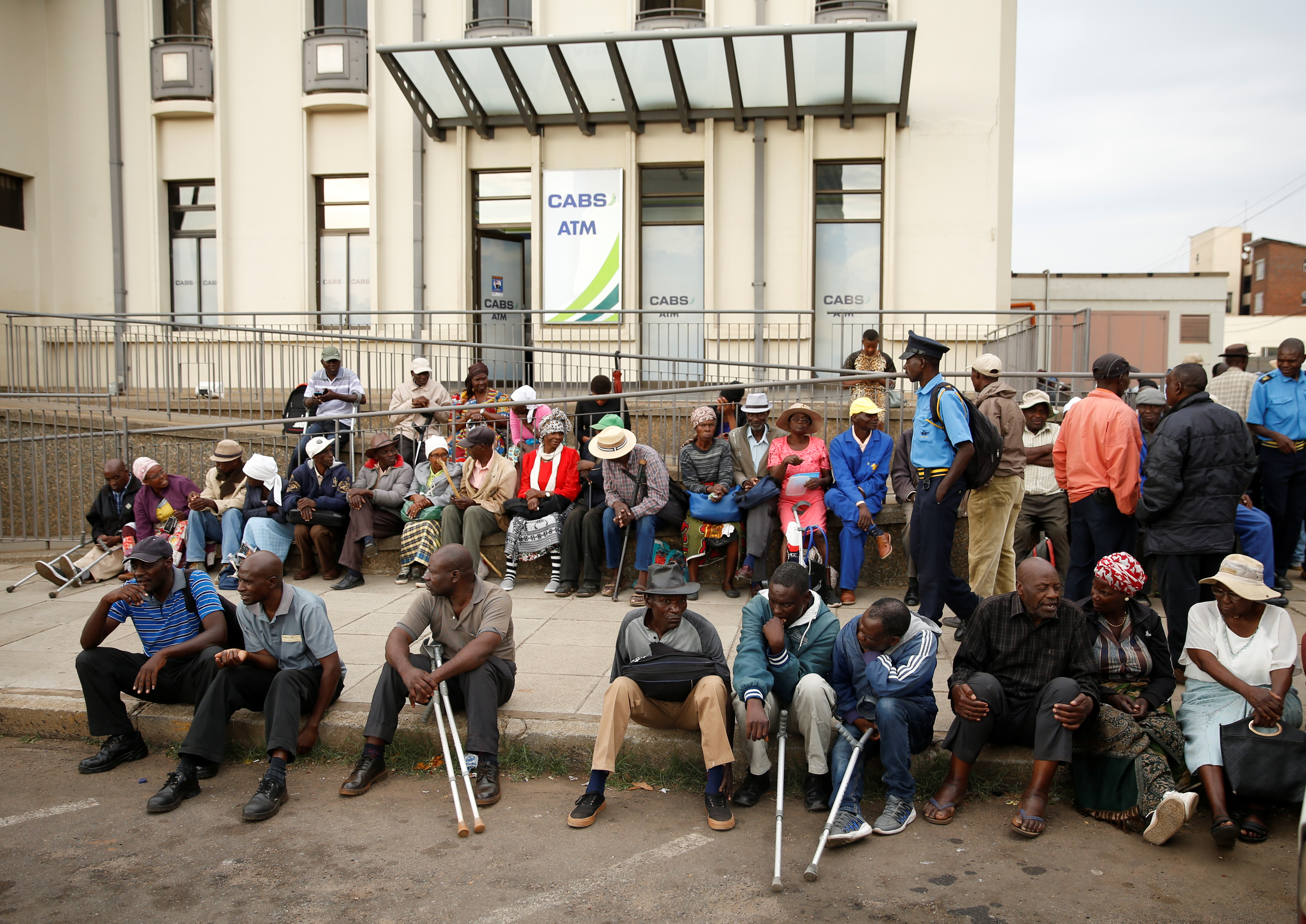 People queue to withdraw money from a bank in Harare