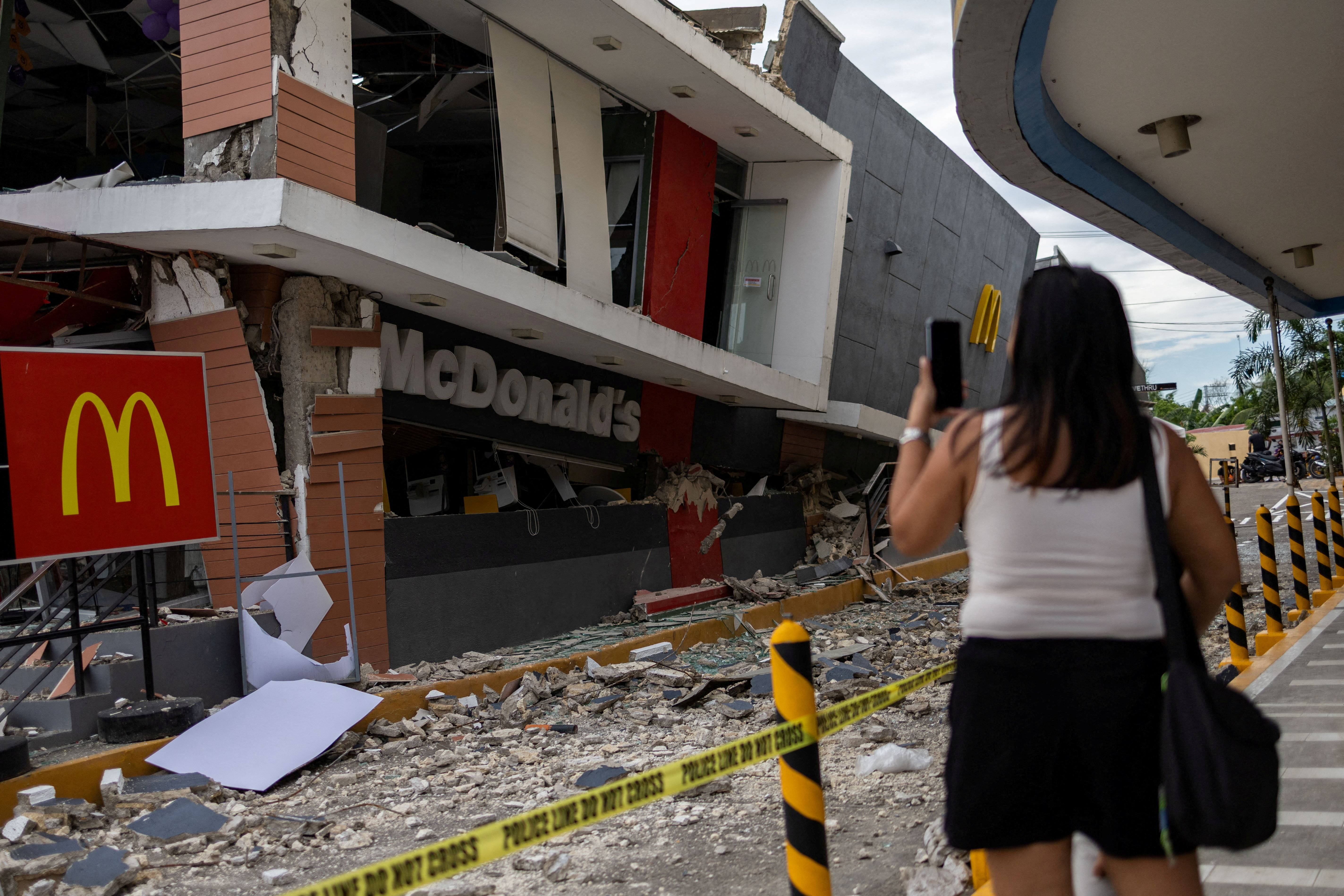 A woman takes a photo of a damaged McDonald’s store in the aftermath of a magnitude 6.9 quake in Bogo City, Cebu, the Philippines, on October 1, 2025