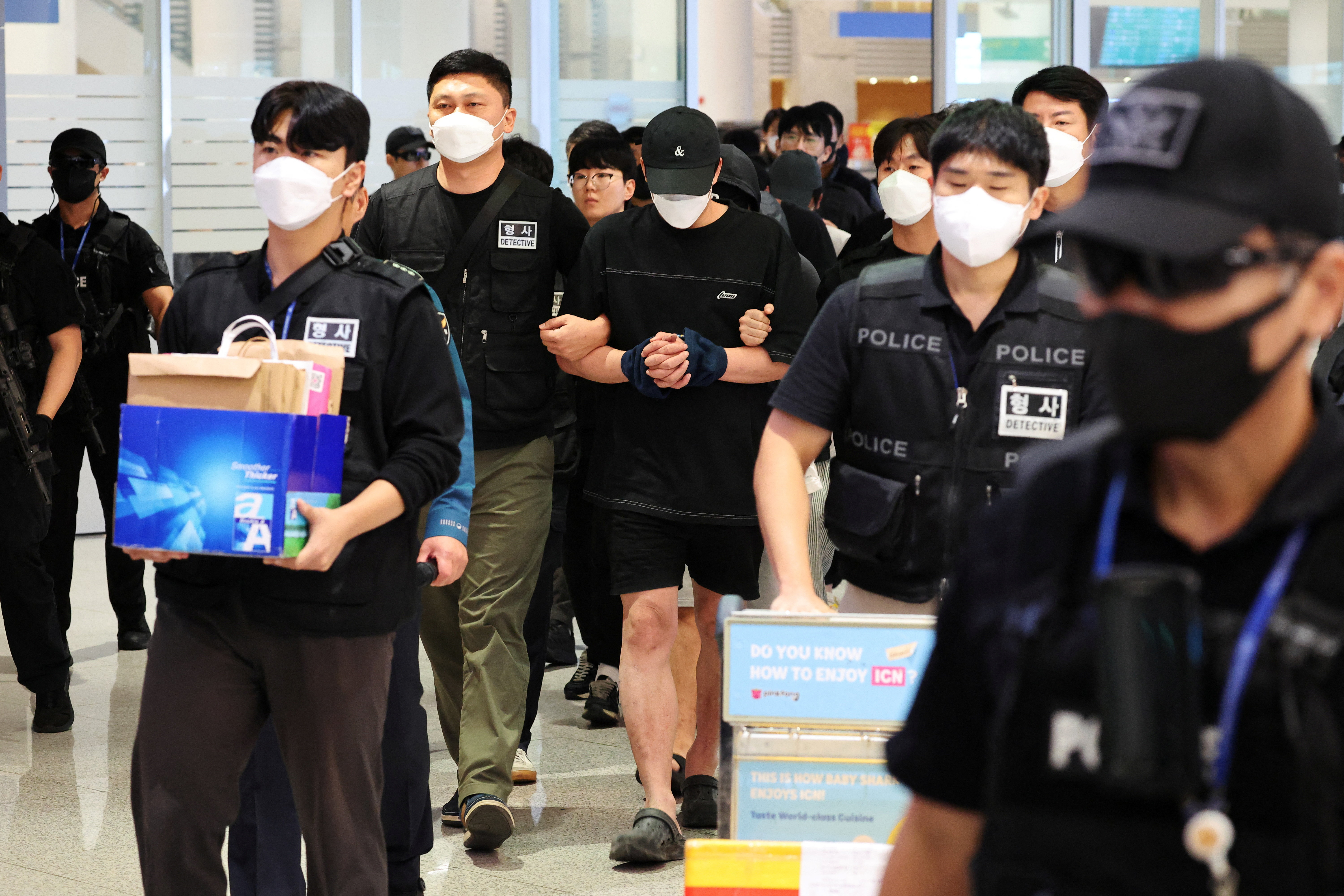 Police officers escort South Korean deportees suspected of being involved in online scam operations in Cambodia upon their arrival at the Incheon International Airport in Incheon, South Korea, October 18, 2025. REUTERS/Kim Hong-Ji