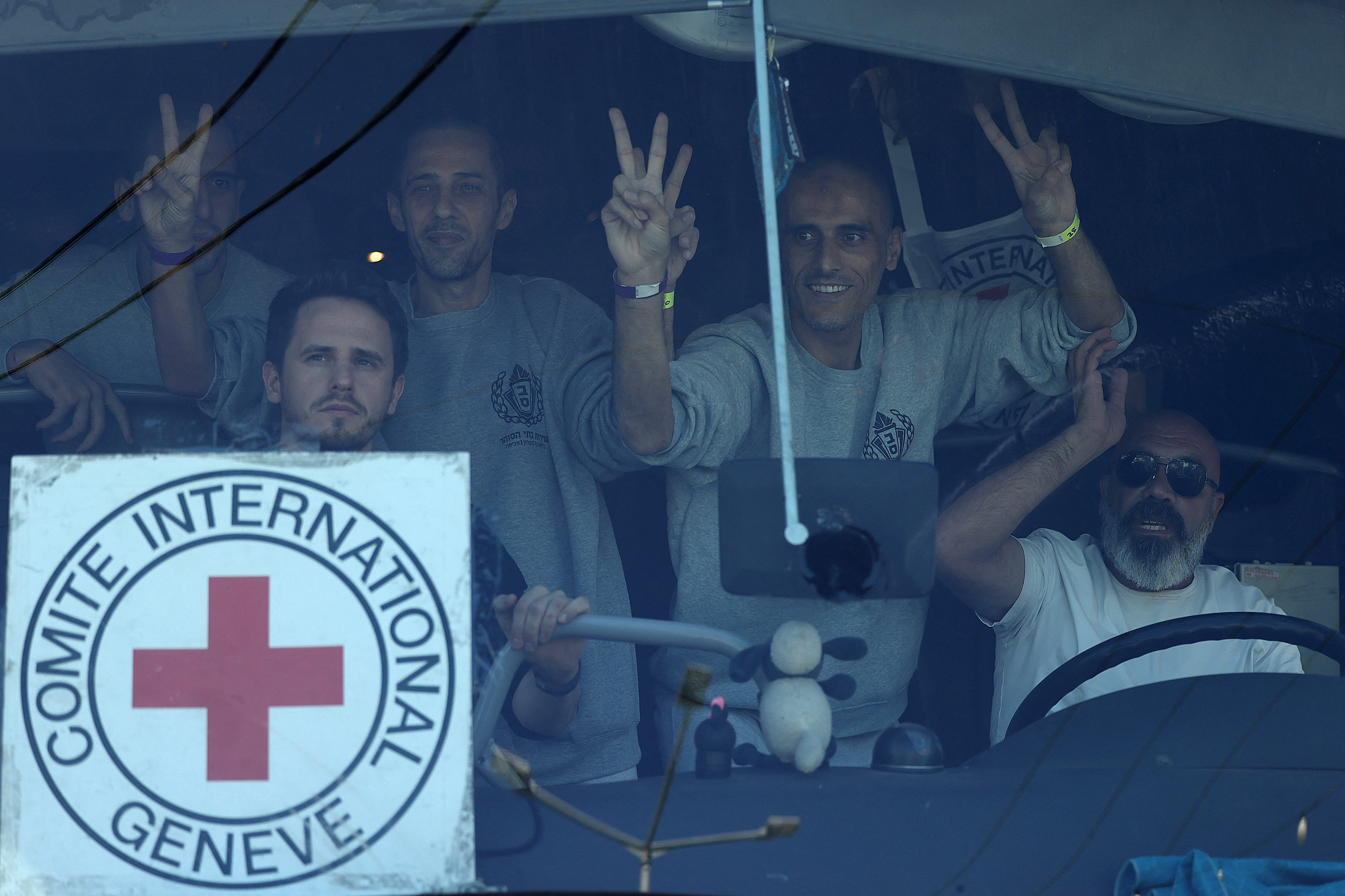 Palestinian men gesture from inside a bus after being released from the Ofer military prison located between Ramallah and Beitunia in the occupied West Bank on October 13, 2025, in exchange for hostages held by Hamas in Gaza since the October 7 attacks