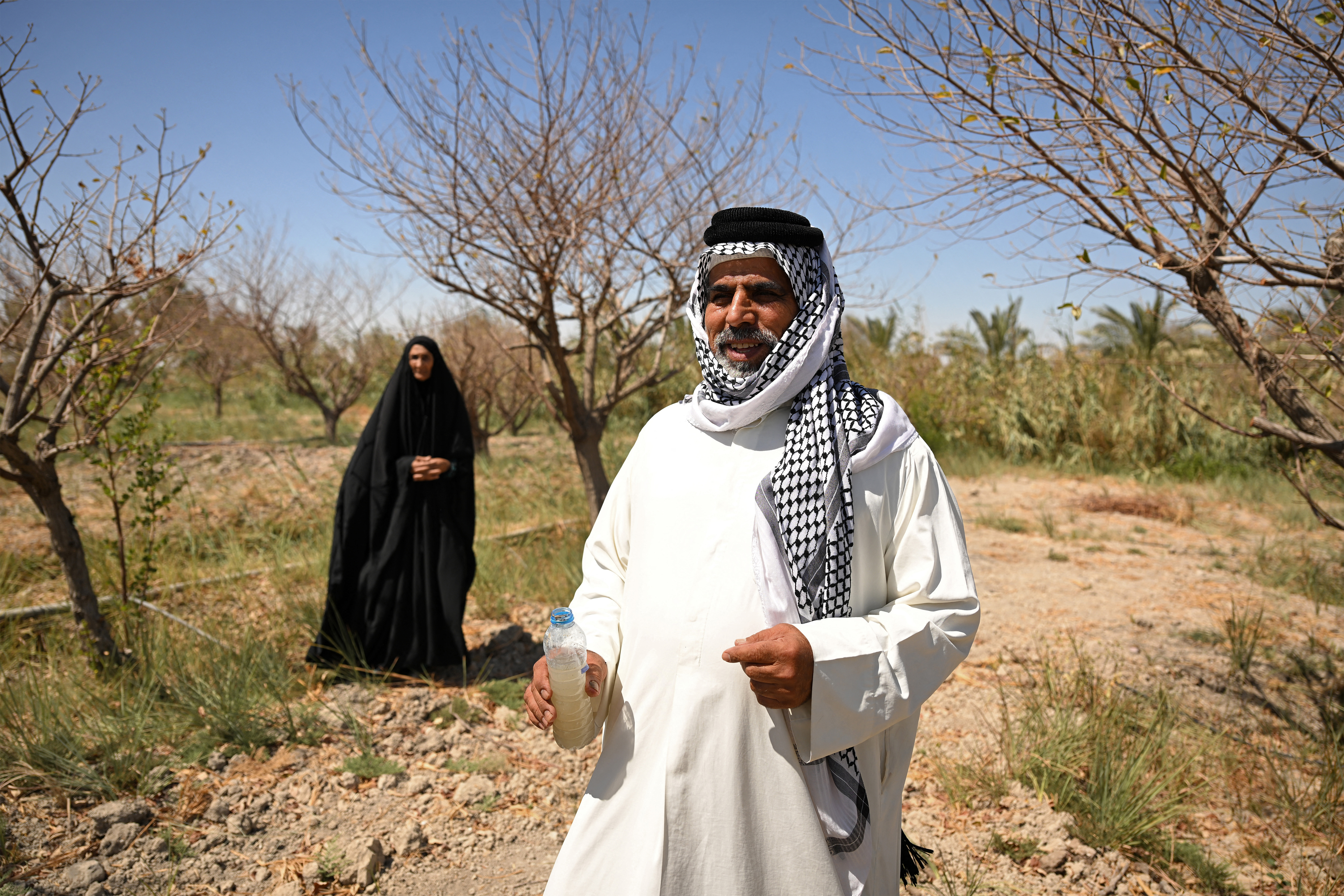 A man holds a bottle of cloudy water in the farm of Iraqi farmer Zuleikha Hashim Taleb