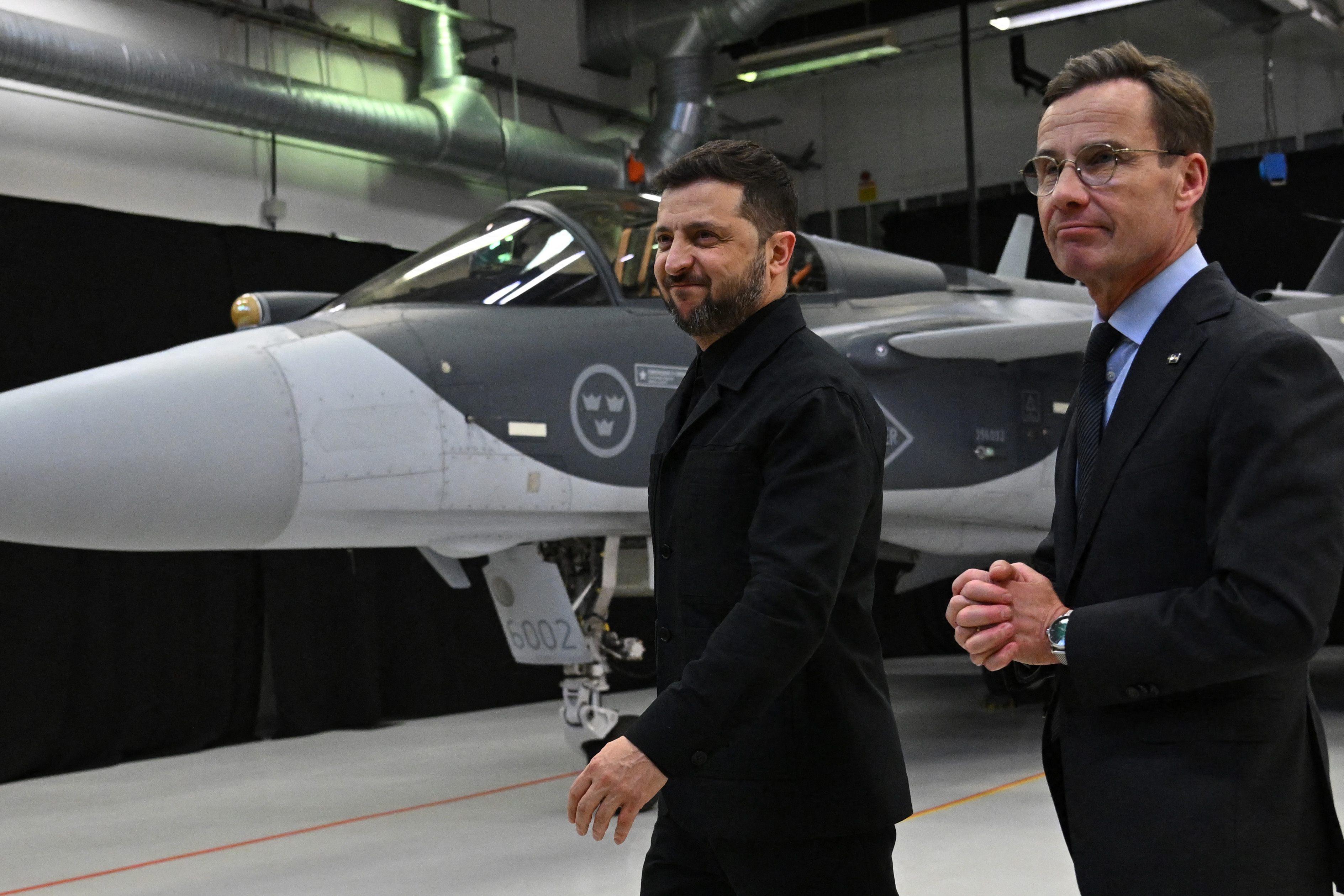 Swedish Prime Minister Ulf Kristersson, right, and Ukrainian President Volodymyr Zelenskyy walk past a Gripen fighter jet after they delivered a joint news conference in Linkoping, Sweden