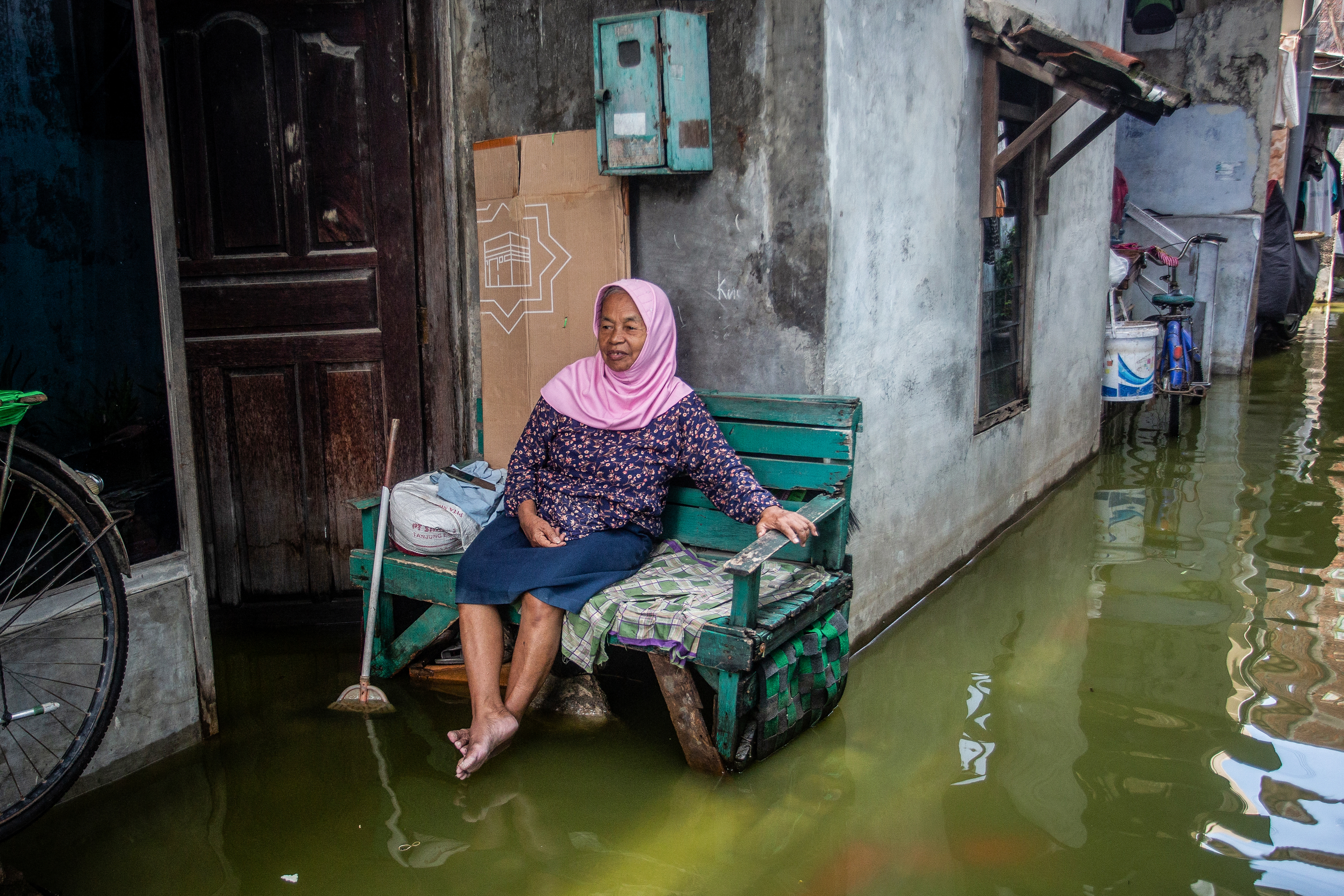 A woman sits outside her house after heavy rains induced floods in Semarang, Central Java