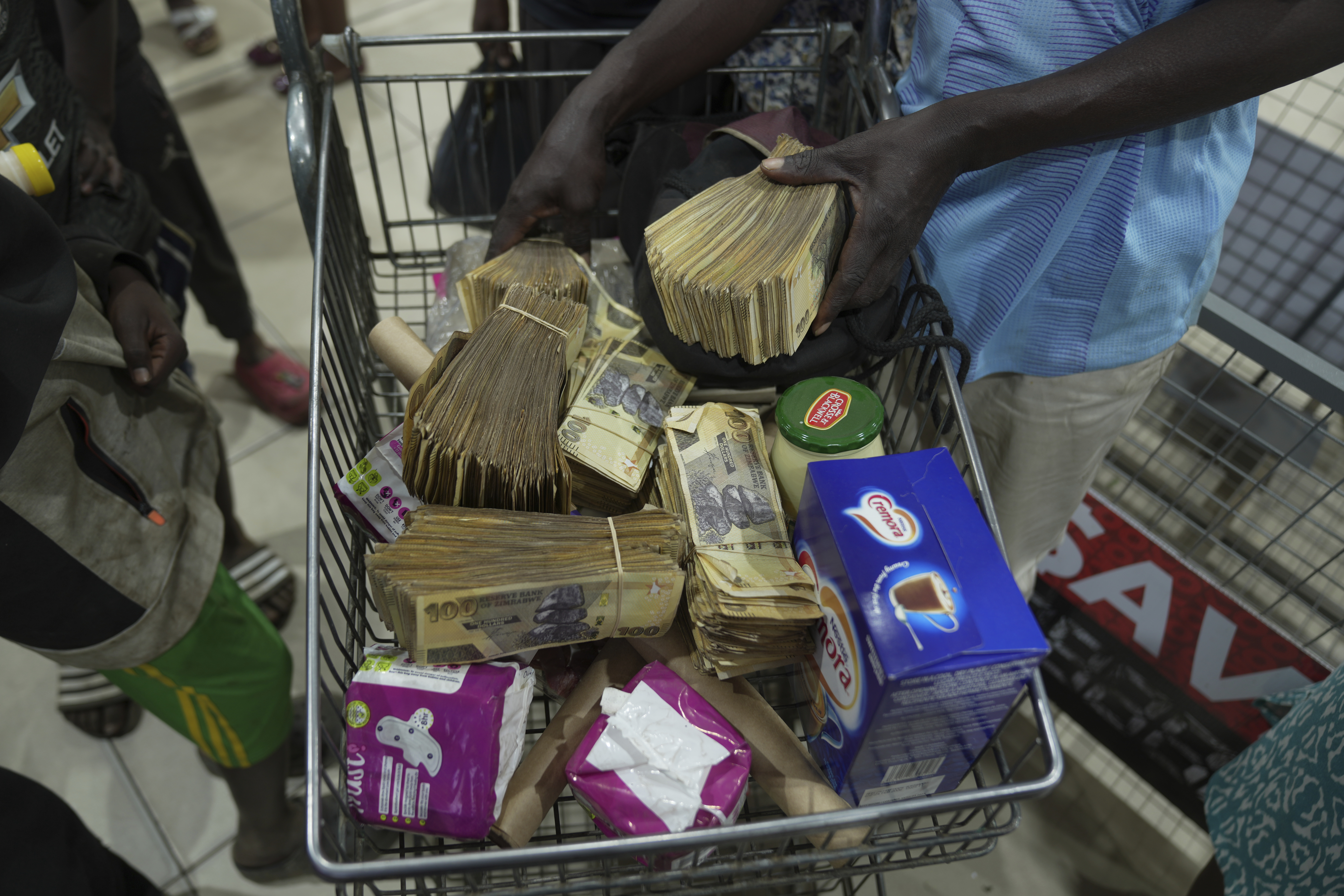 A man uses old Zimbabwean dollar notes to buy groceries in Harare. Zimbabwe’s currency is weak against foreign currencies, so many locals prefer to use the US dollar