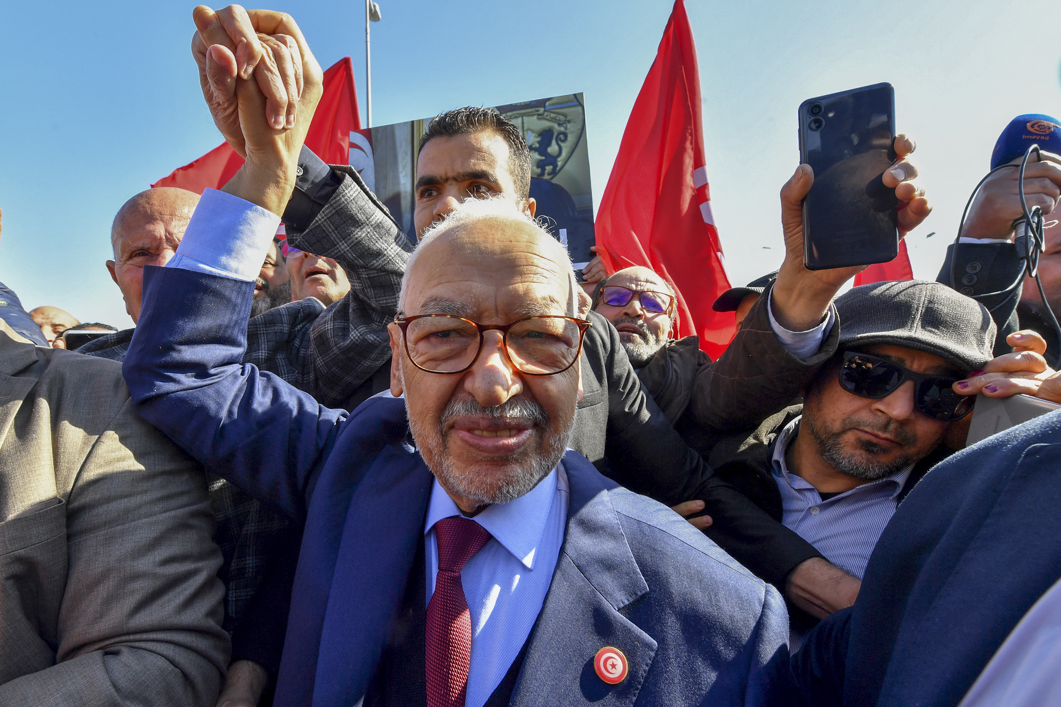 The head of Tunisia's Islamist movement Ennahdha Rached Ghannouchi greets supporters upon arrival to a police station in Tunis ,on February 21, 2023, in compliance to the summons of an investigating judge. (Photo by FETHI BELAID / AFP)