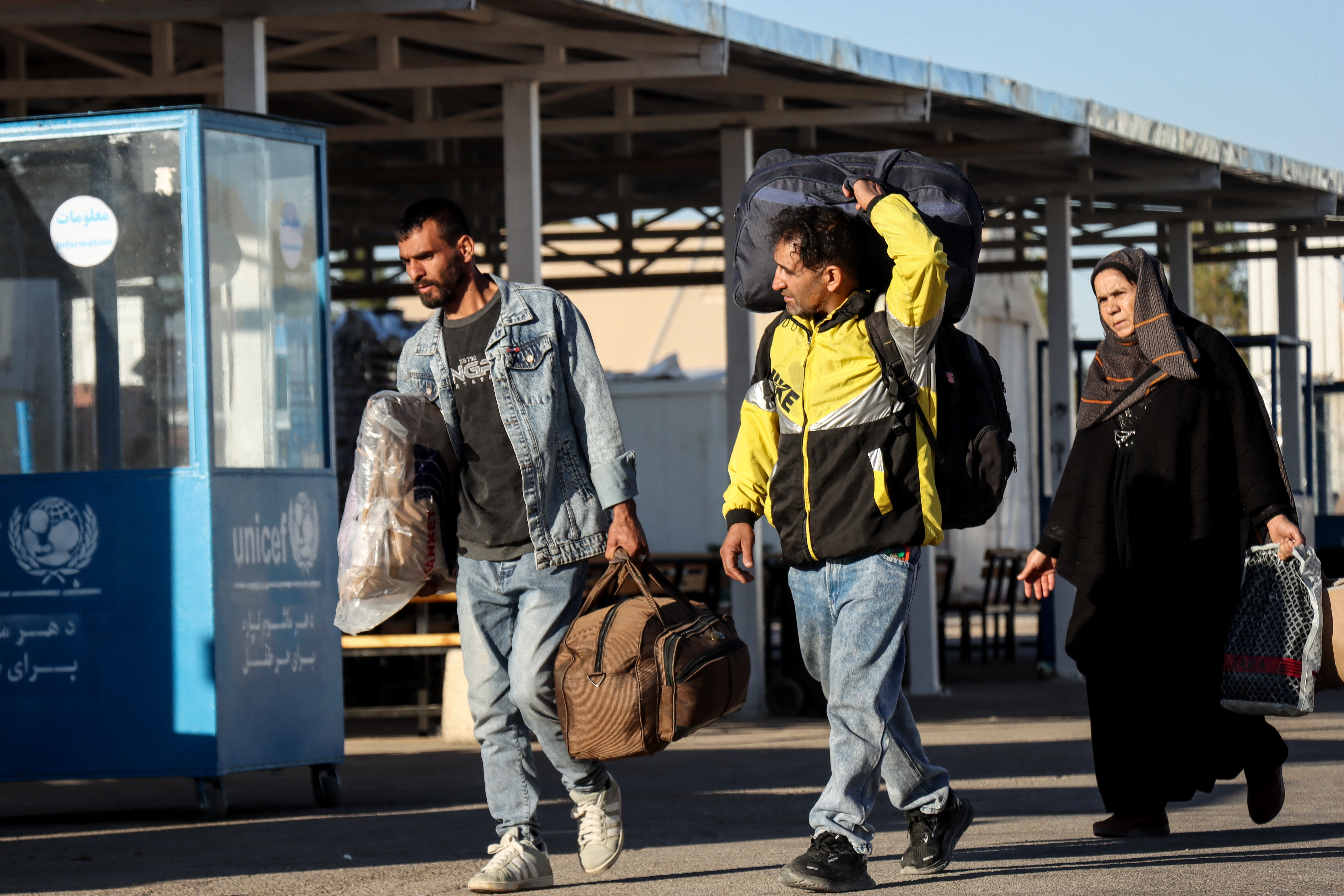 Afghan returnees walk upon their arrival from Iran at the closed registration centre of the United Nations High Commissioner for Refugees (UNHCR) at the Zero Point Islam Qala border crossing between Afghanistan and Iran, in Herat province, on November 5, 2025. The United Nations on November 4 suspended operations at a key border crossing between Afghanistan and Iran because of new Taliban government restrictions on Afghan women workers, a UN official said. (Photo by Mohsen KARIMI / AFP)