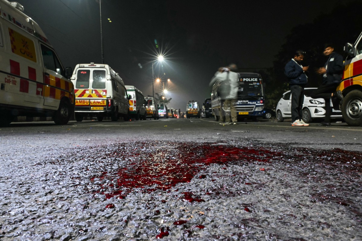 Ambulances are kept on standby on a blood-spattered road at the blast site after an explosion near the Red Fort in the old quarters of Delhi on November 10, 2025. At least 13 people were killed and 19 injured when a car exploded in the heart of the Indian capital, New Delhi’s deputy fire chief told AFP
