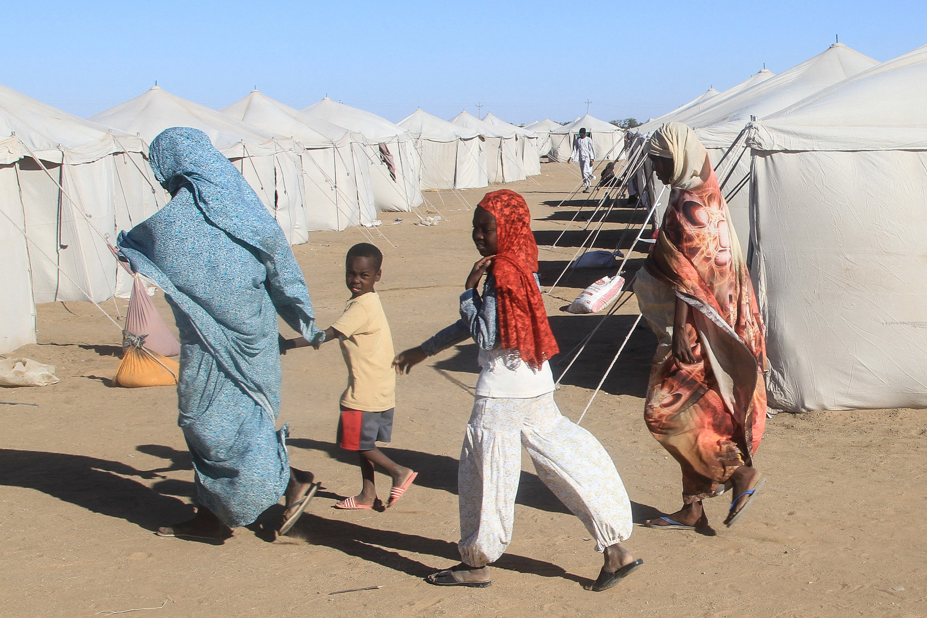 Sudanese walk past tents at a displacement camp.