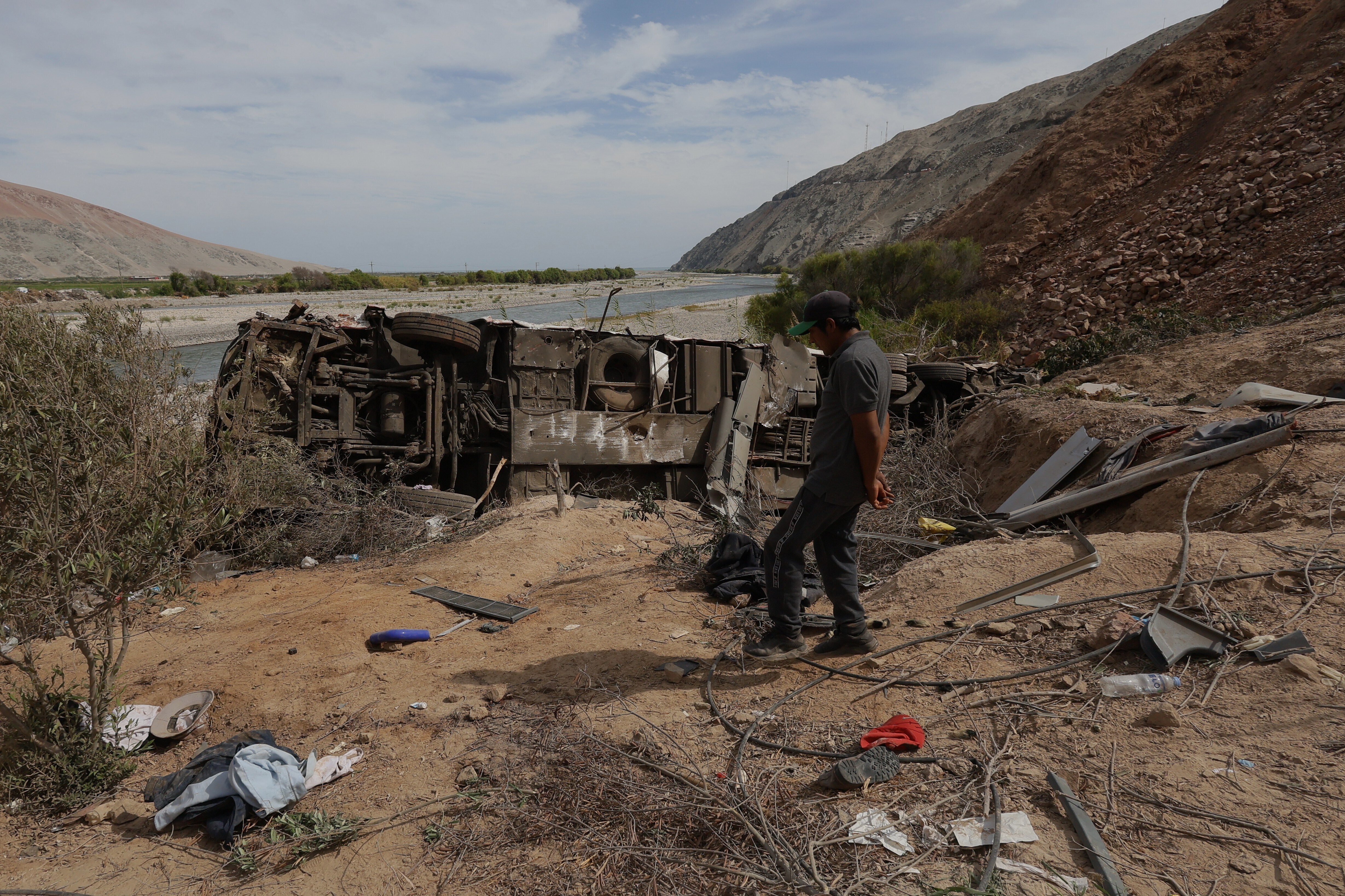 A man walks by a passenger bus after a deadly crash with a pickup truck in Peru's Arequipa region on November 12, 2025 [Kiara Tapia/AP]
